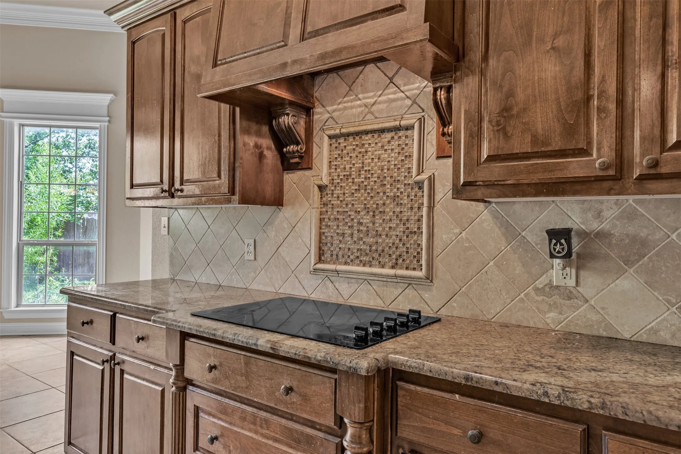 Wood-finish cabinetry paired with granite-finish countertops and a black electric cooktop