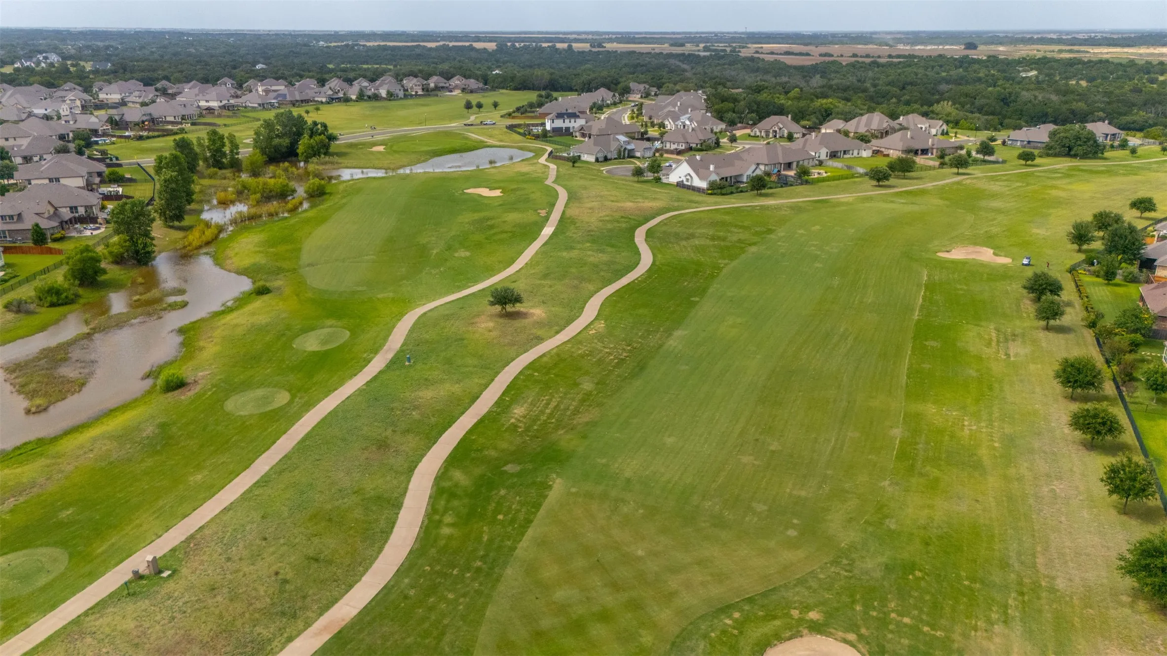 Expansive golf course property featuring manicured fairways, golf cart paths, and scattered mature trees