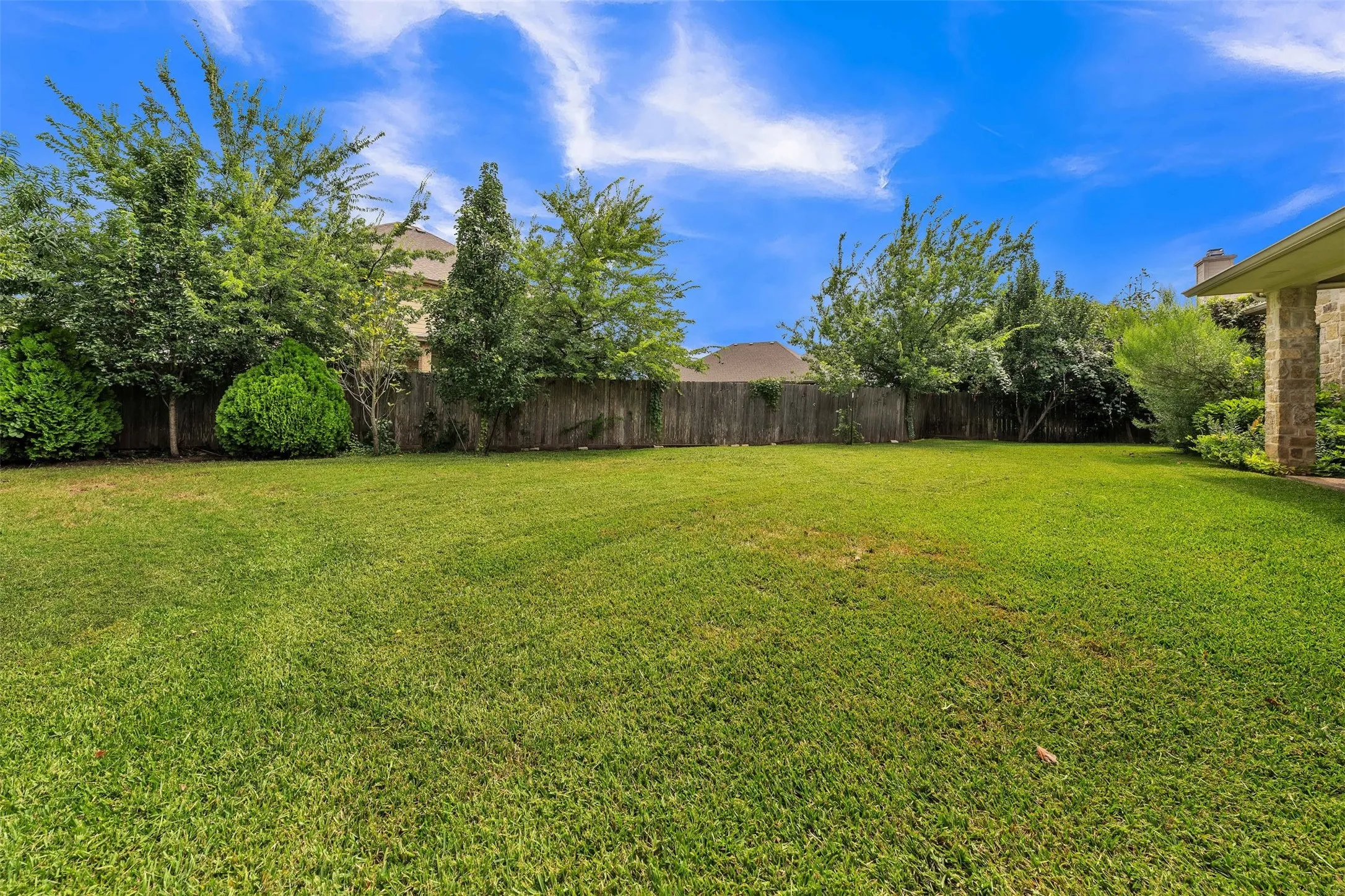 Expansive backyard featuring a lush lawn, privacy fencing, and mature perimeter landscaping