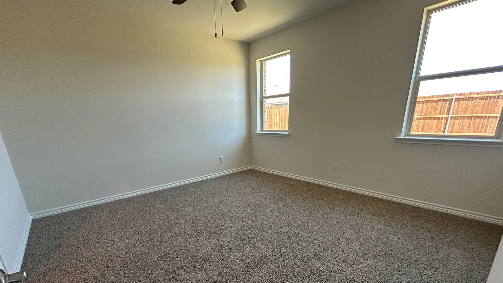 Carpeted room featuring multiple windows, a ceiling fan, and painted walls