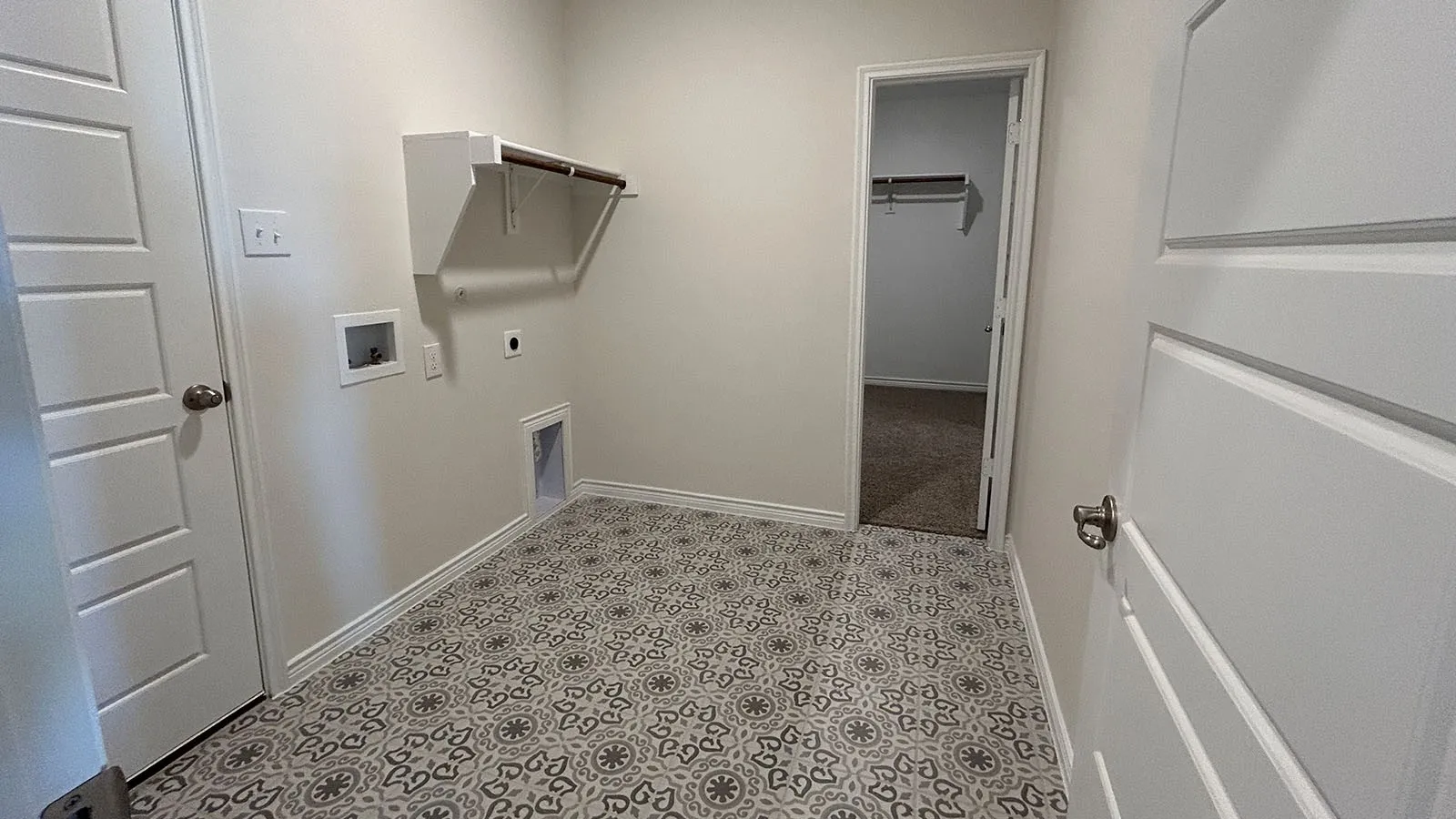 Patterned tile flooring, built-in shelving, clothes hanging rod, and laundry hookups