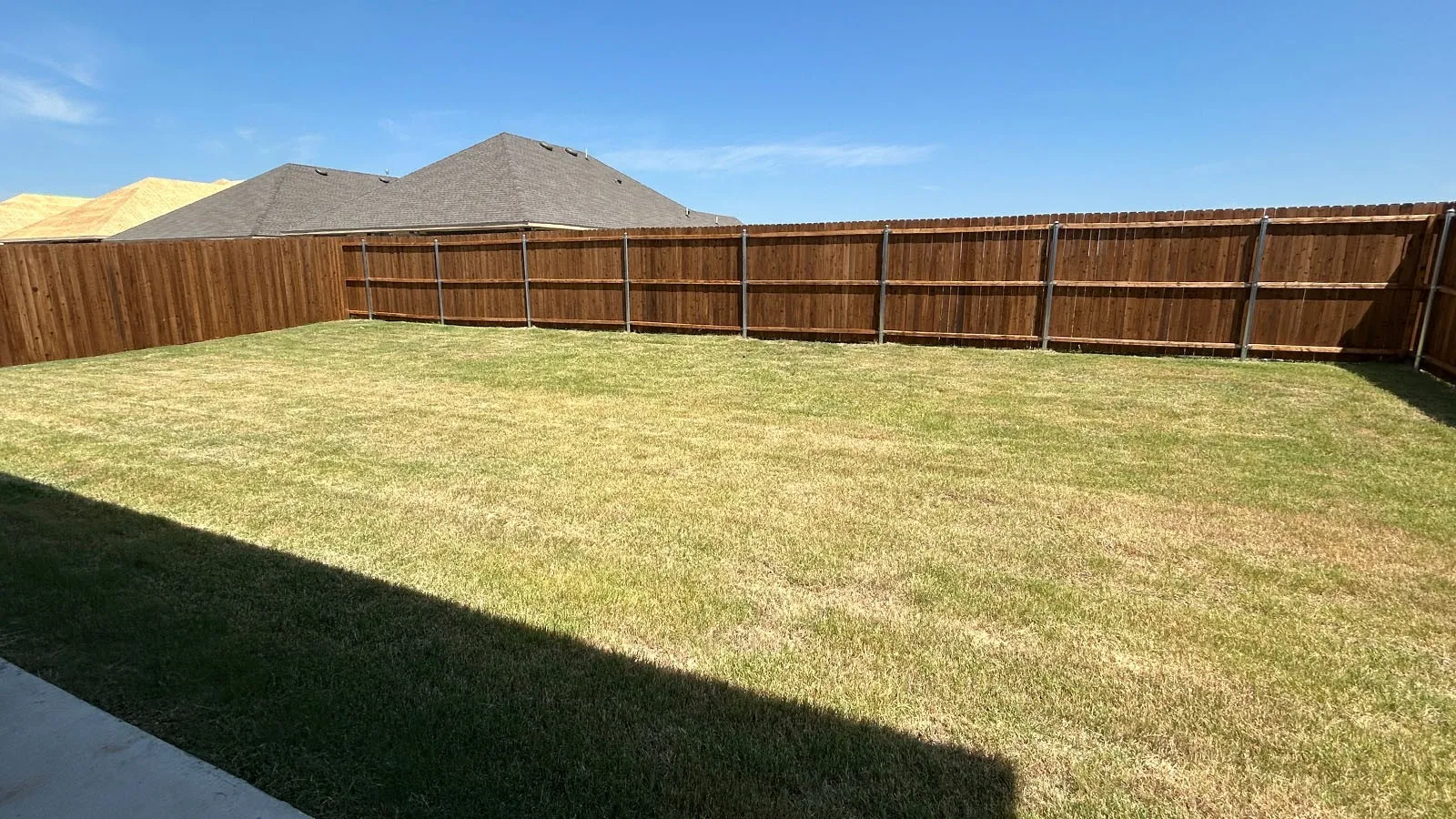 Expansive backyard featuring a wood privacy fence and a substantial lawn area