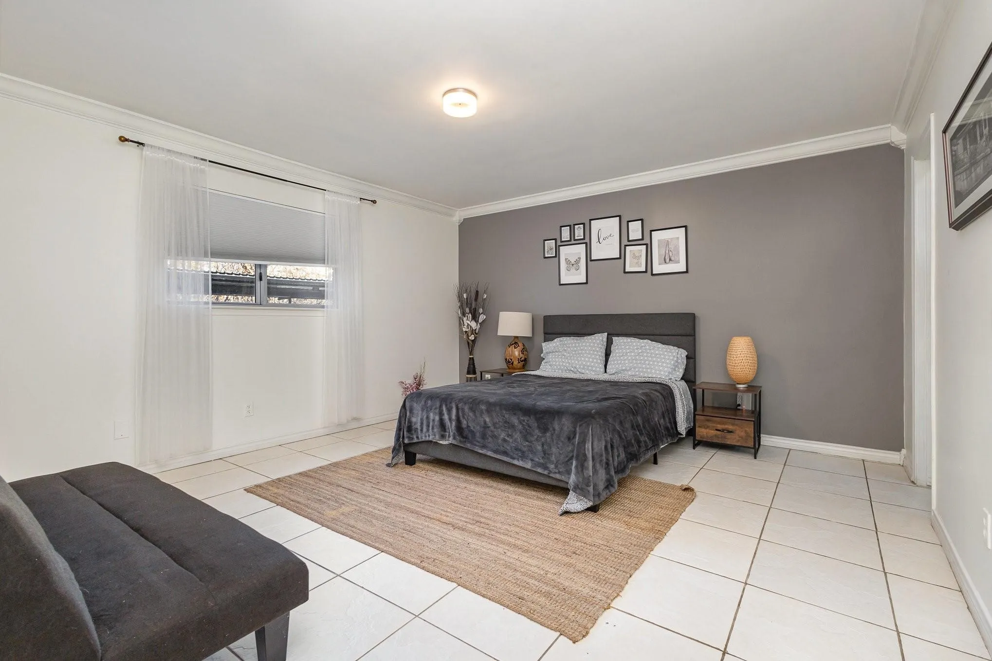 Bedroom featuring a contrasting accent wall, white ceramic tile flooring, crown molding, a window with horizontal blinds, and a flush mount ceiling light