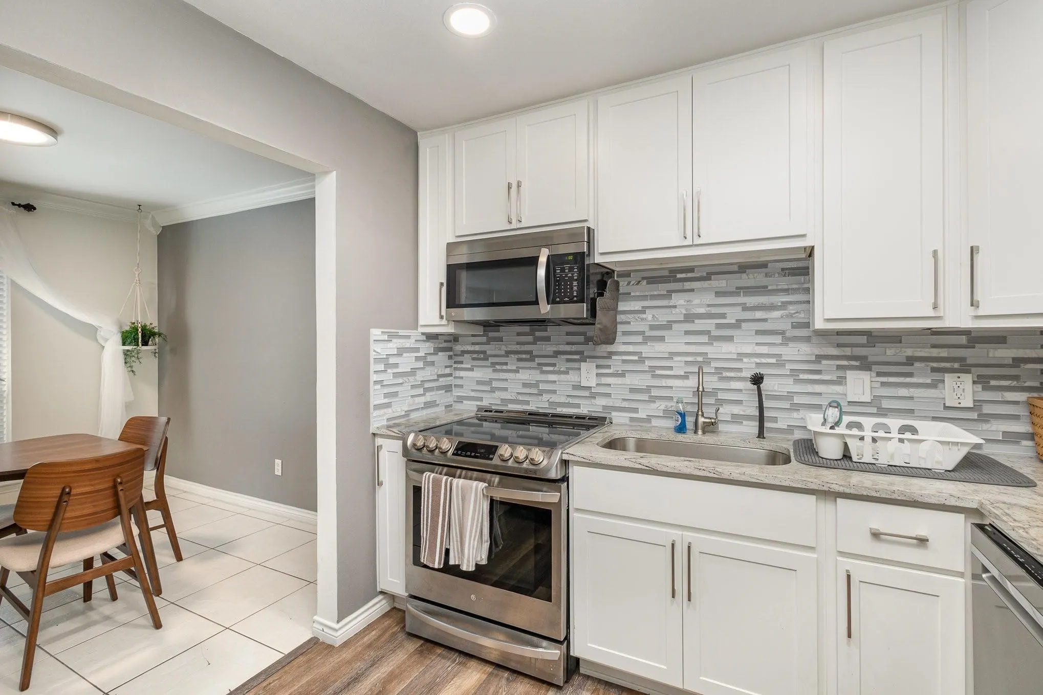 Kitchen featuring stainless steel appliances, white cabinetry, and a mosaic tile backsplash