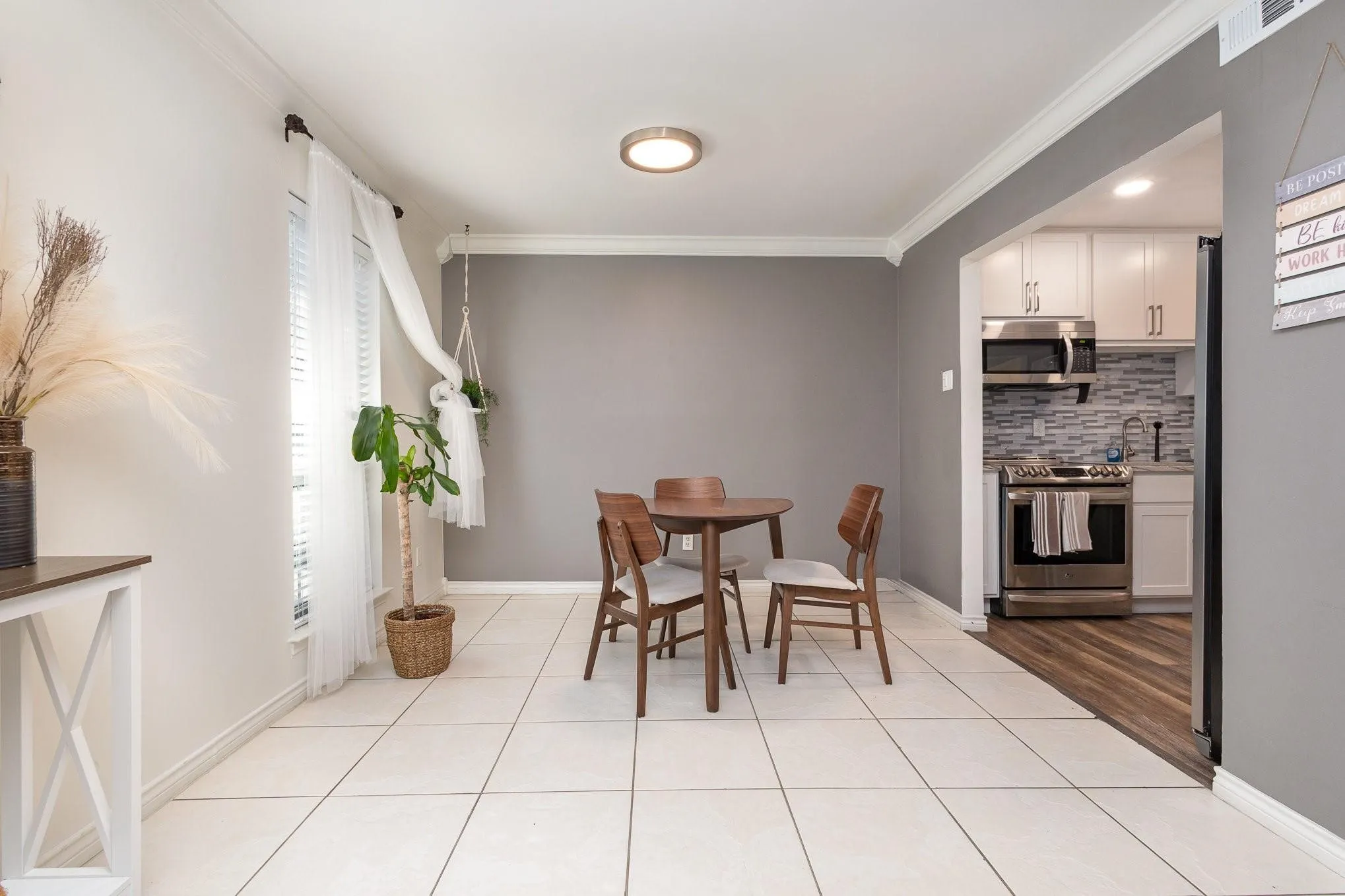Dining area featuring white tile flooring, a window with blinds, and crown molding