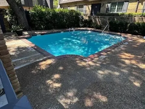 Rectangular swimming pool featuring a brick coping and concrete surround