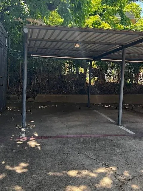 Carport parking space featuring a metal roof, support columns, and concrete flooring