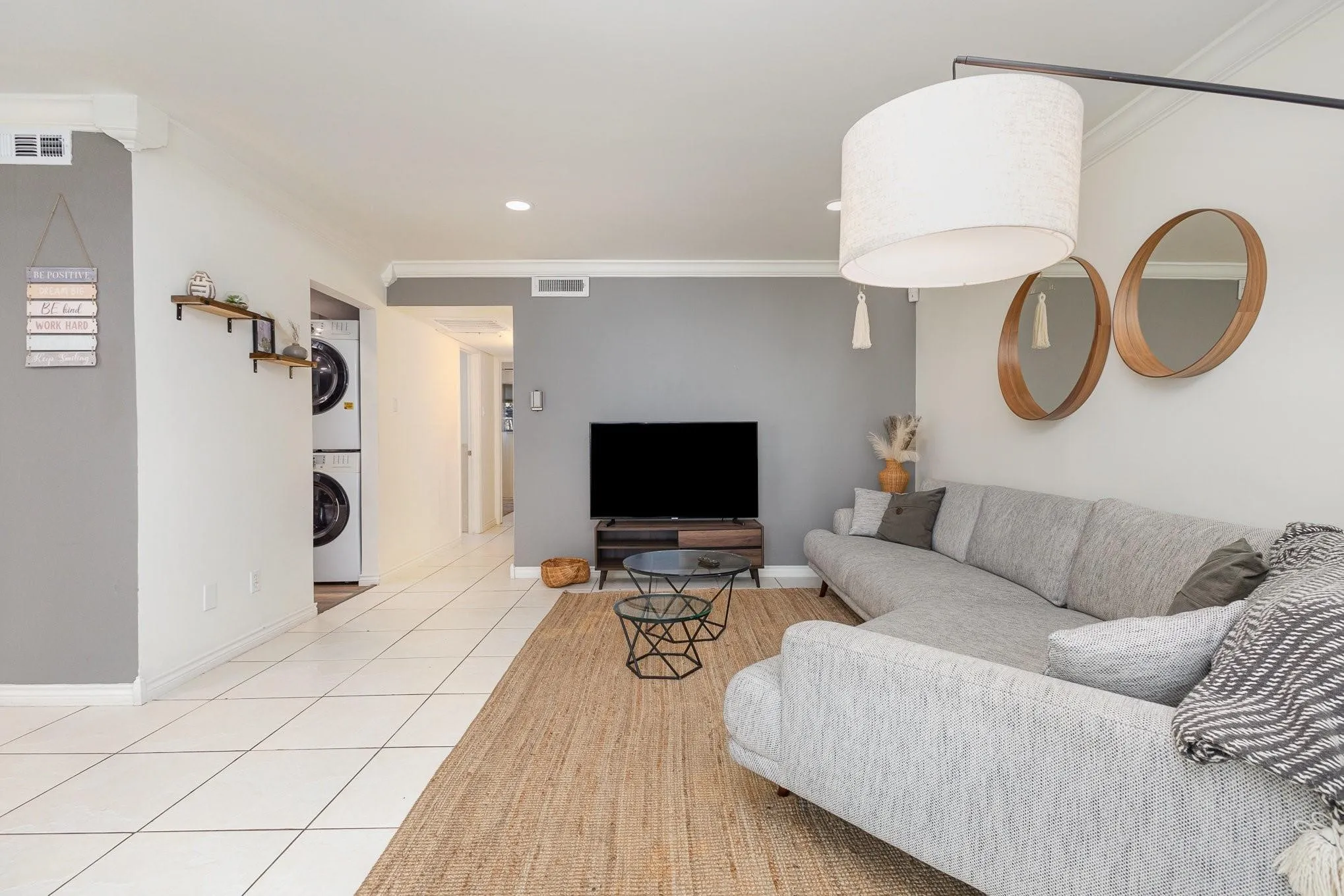 Open-concept living space with white tile flooring and a contrasting woven area rug