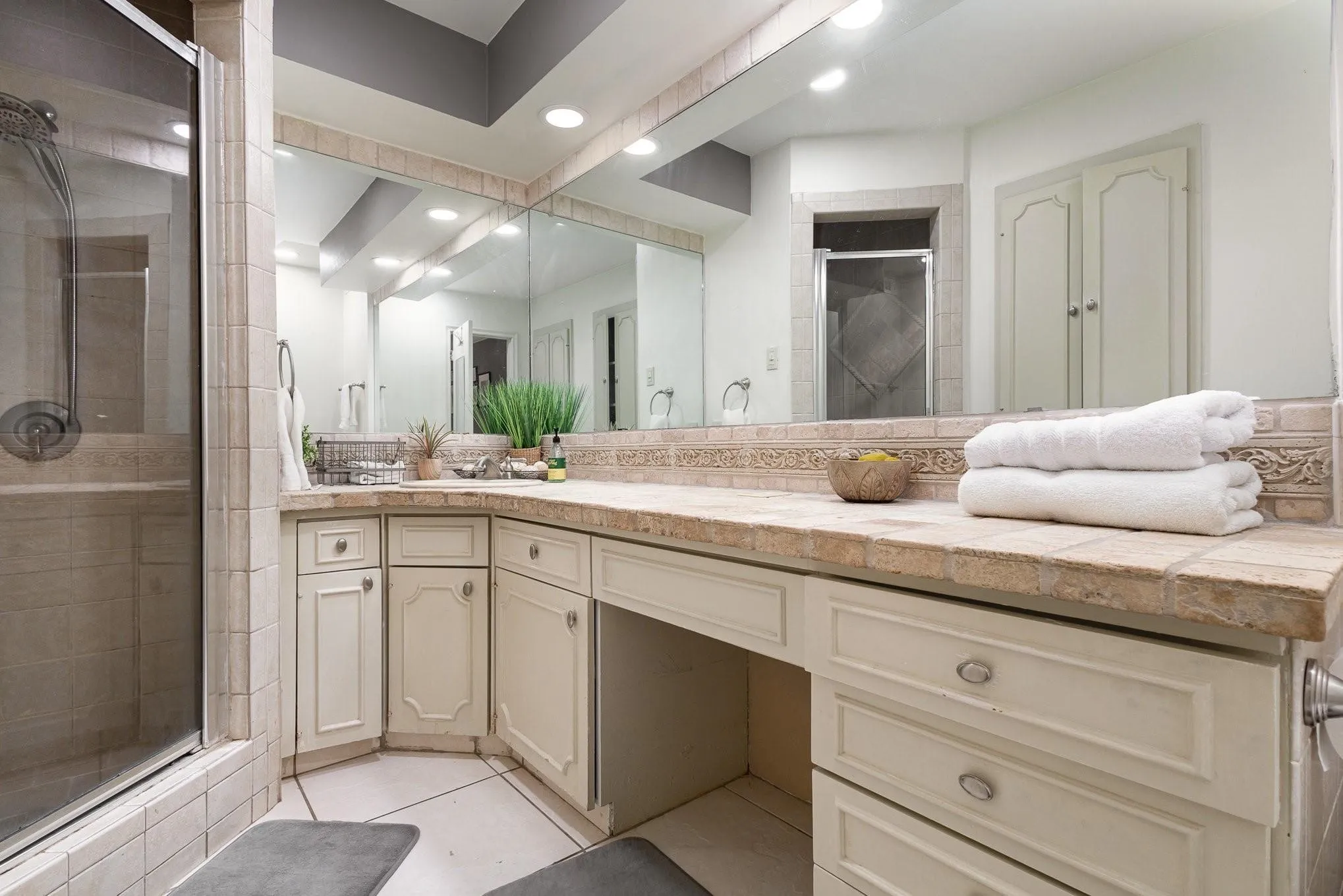 Bathroom vanity with tile countertop, integrated sink, and mirrored wall