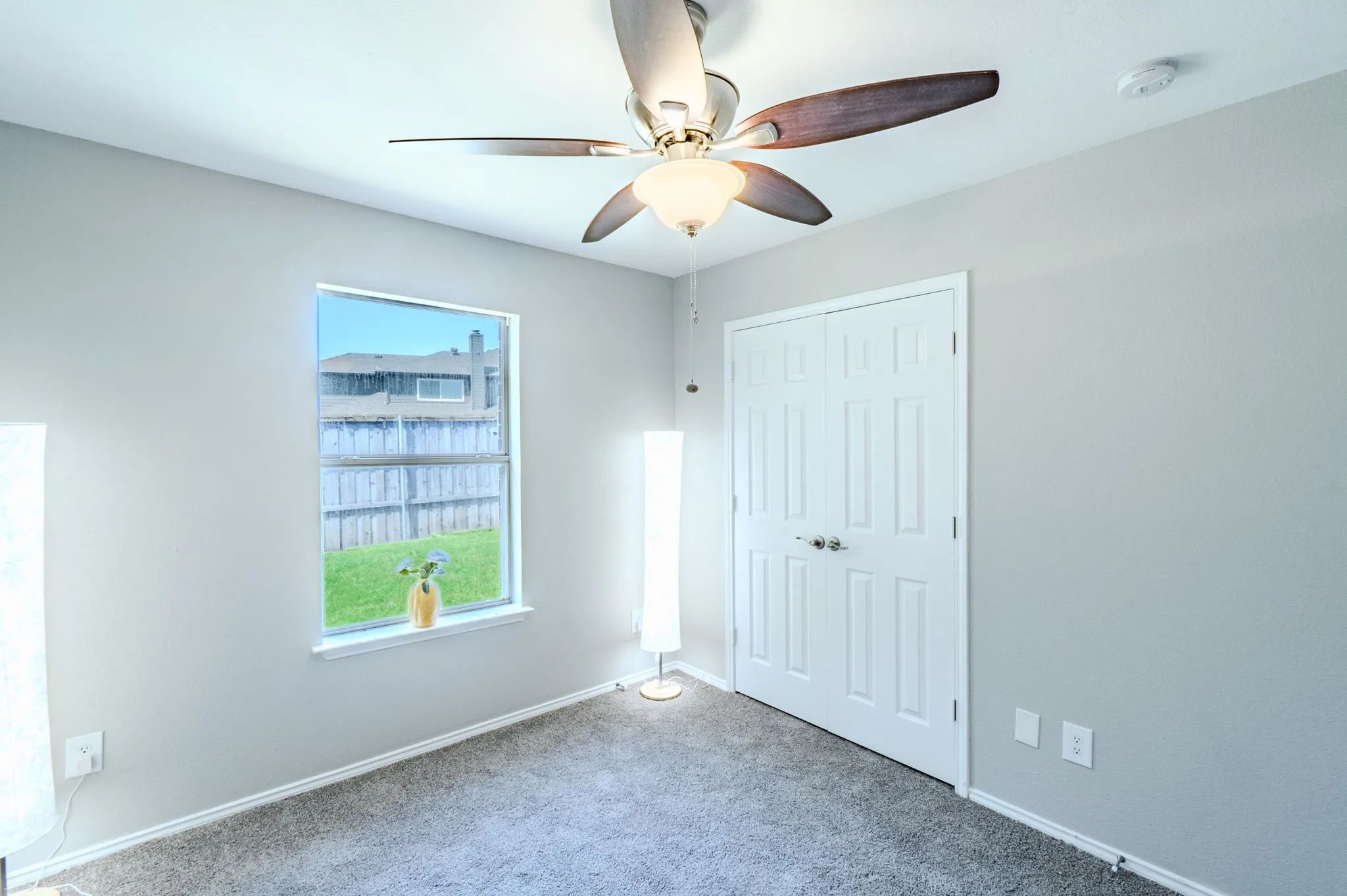 Carpeted room with a ceiling fan, a window, and a paneled bifold closet door
