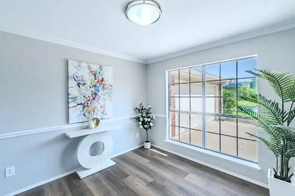 Recessed window with grid pattern, wood-finish flooring, crown molding, and chair rail detailing