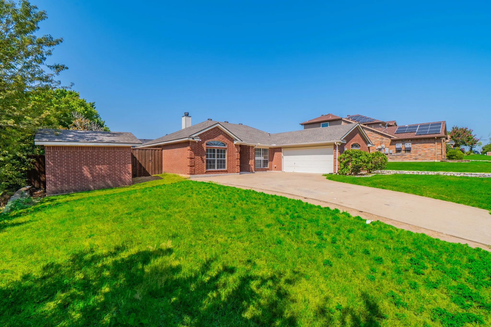Brick exterior residence with an attached garage, concrete driveway, and established front lawn