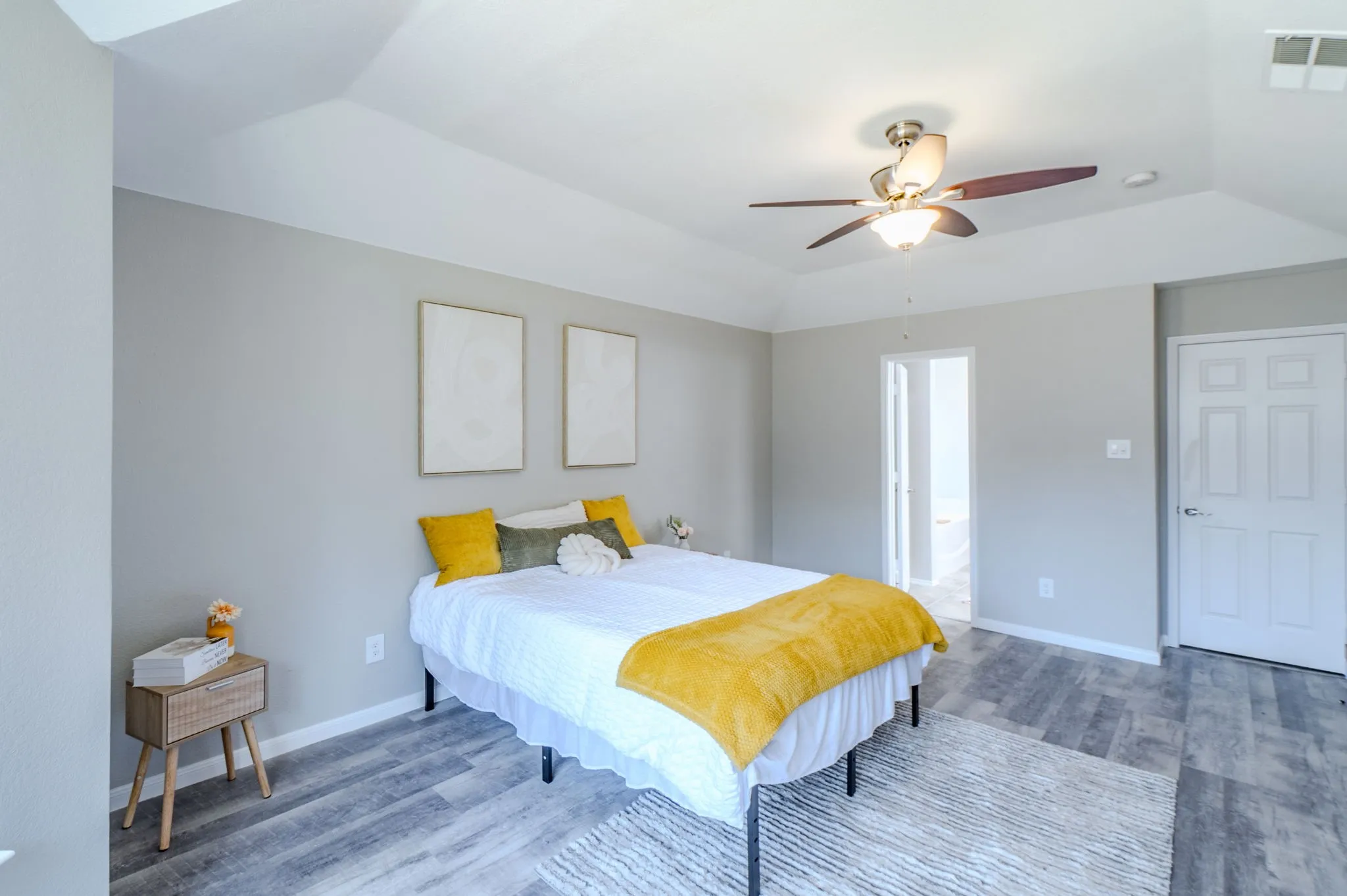 Tray ceiling with a ceiling fan light fixture, light gray wall paint, and wood-finish flooring