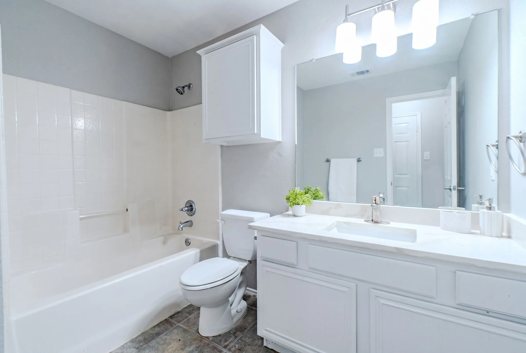 Bathroom featuring a white vanity with an integrated sink, polished chrome faucet, and expansive mirror