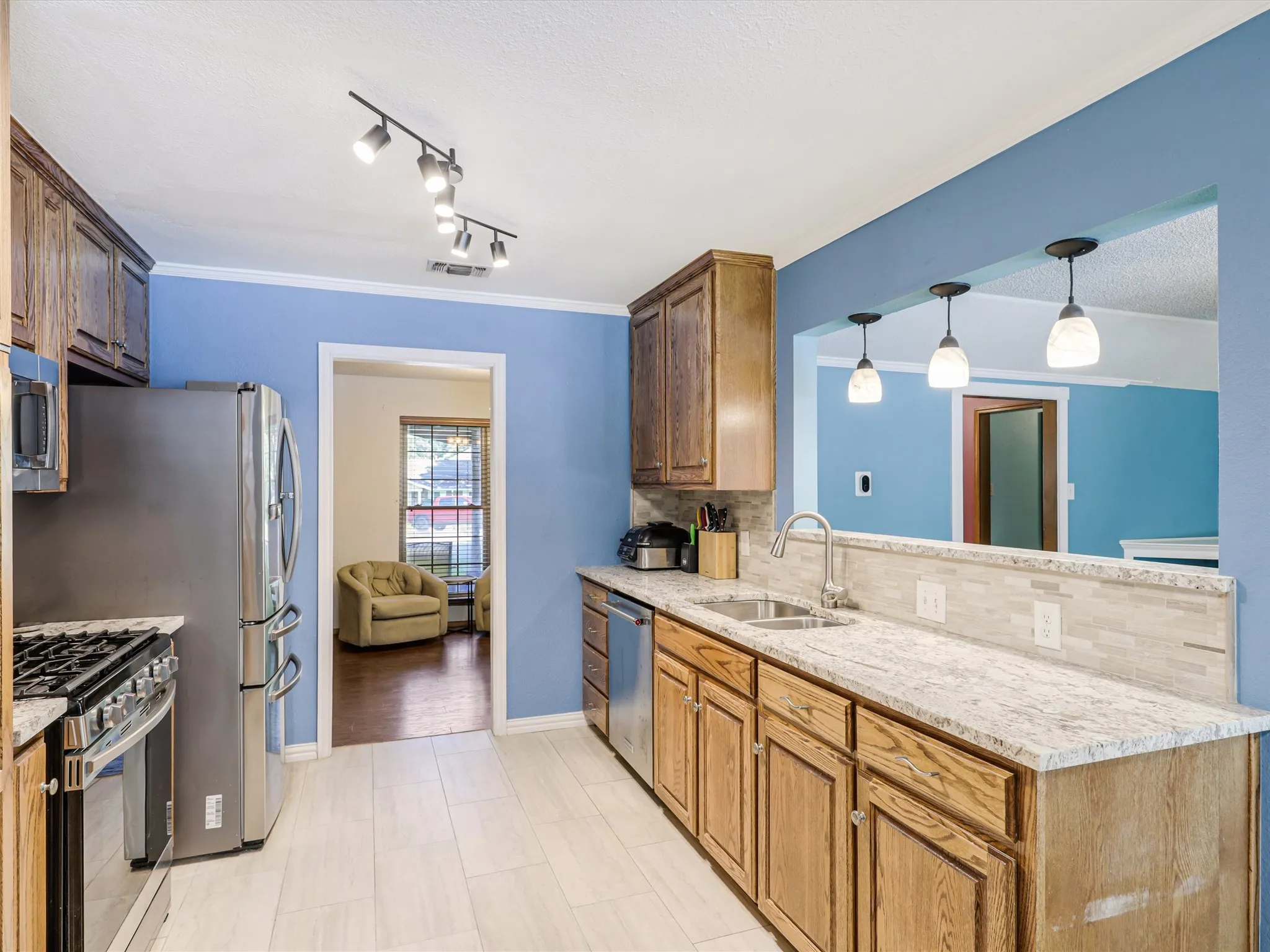 Kitchen featuring wood cabinetry, light-toned countertops, stainless steel appliances, and light tile flooring