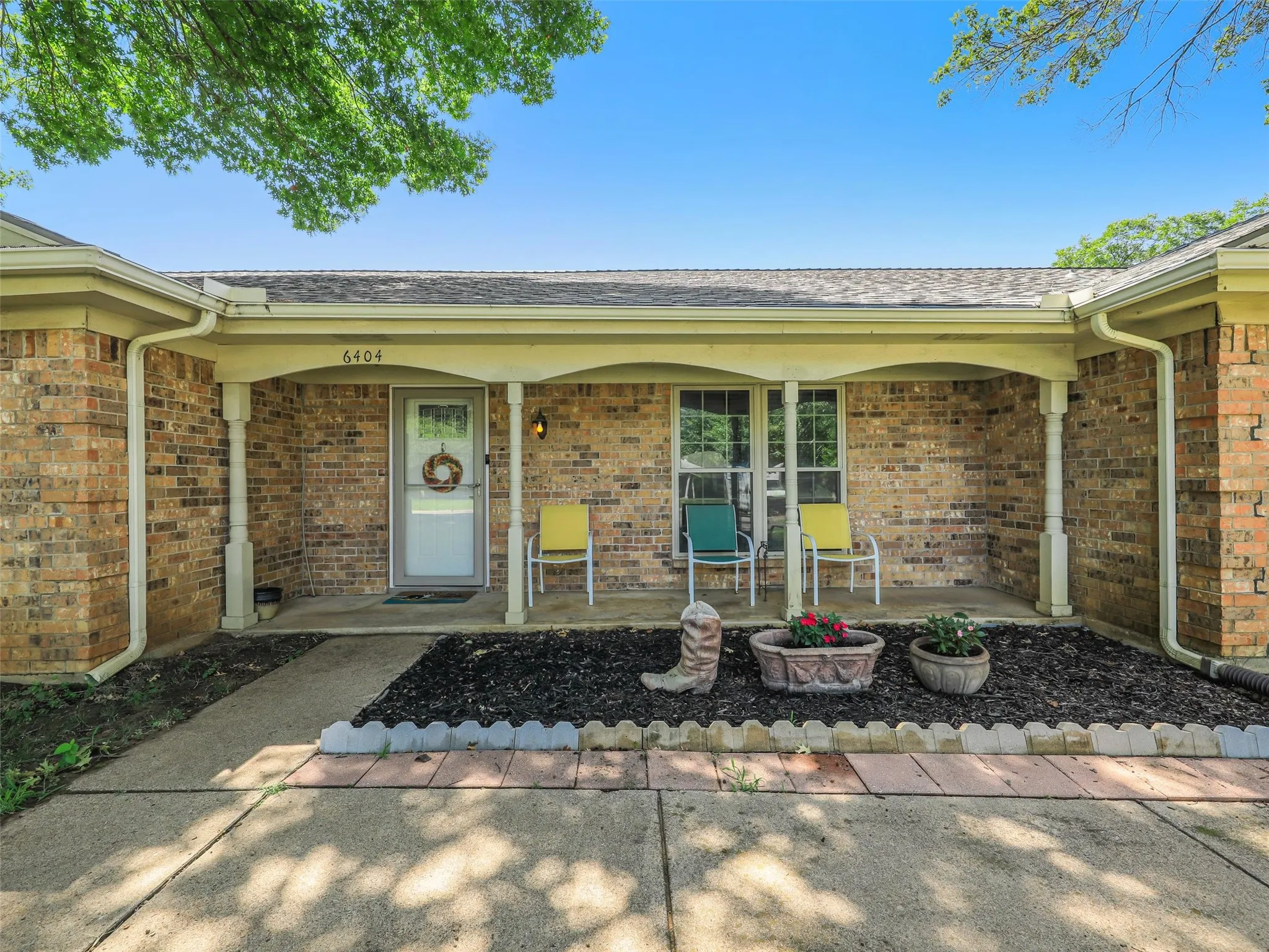 Brick exterior with a covered front porch featuring white columns and a concrete walkway