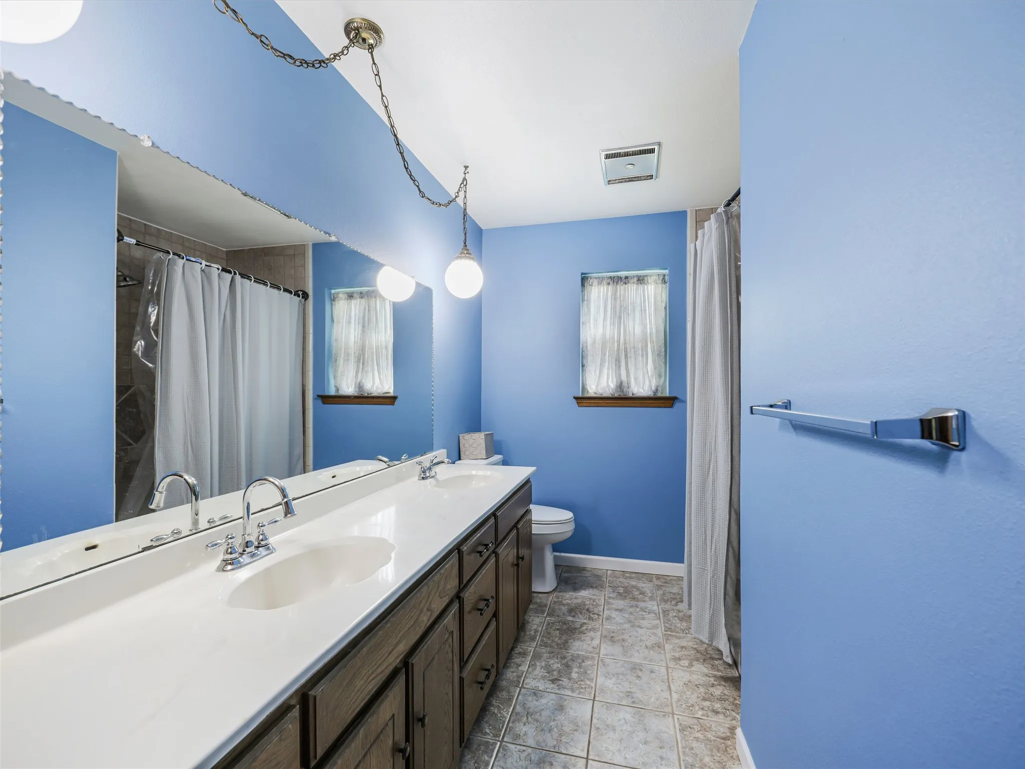Dual vanity with integrated sinks, chrome faucets, and wood-finish cabinetry