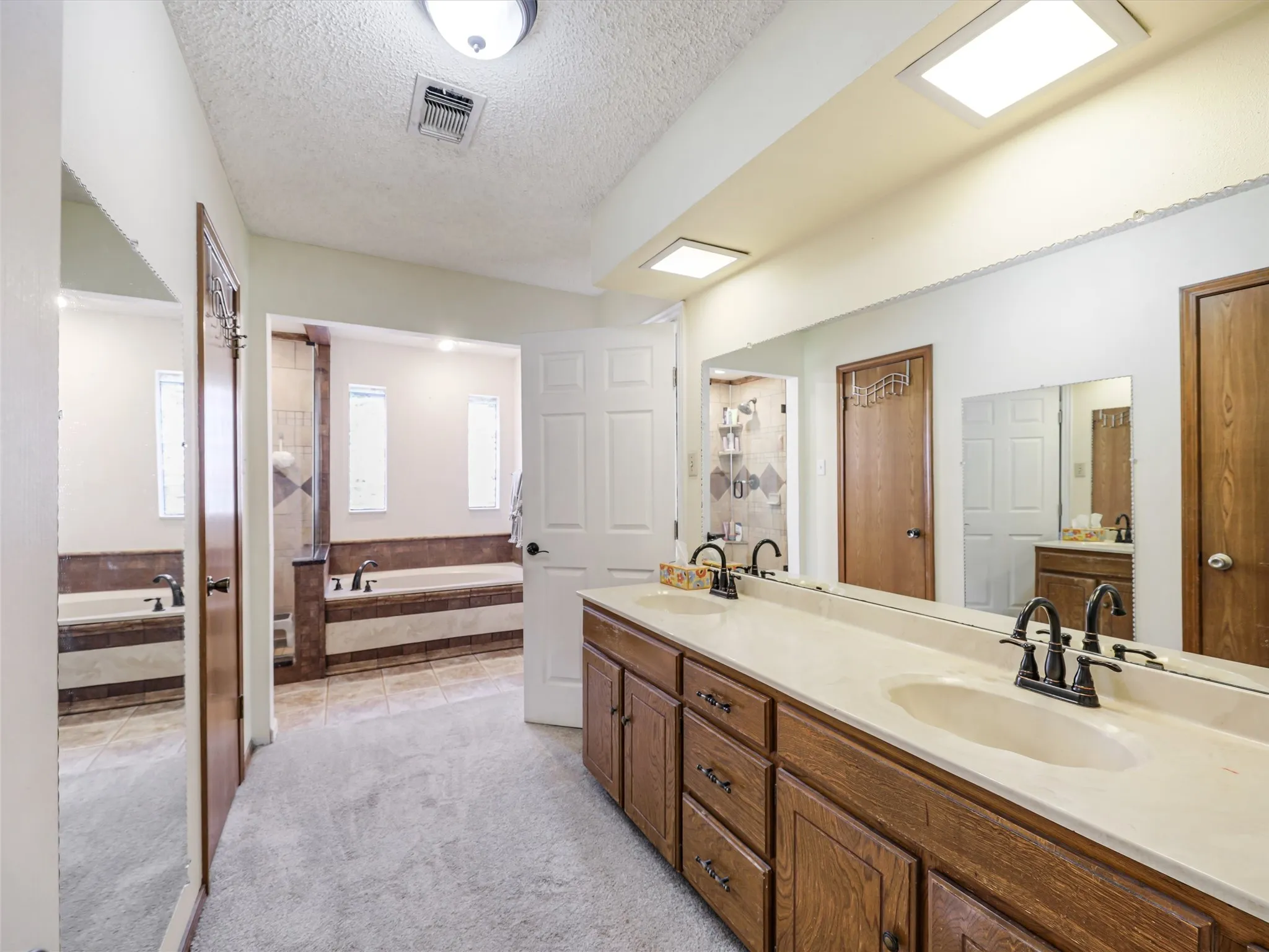 Bathroom featuring a dual vanity with a light-toned countertop, wood-finish cabinetry, and matte black fixtures