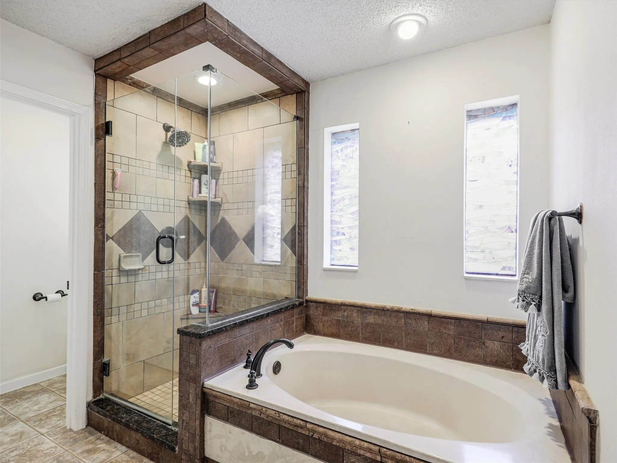 Enclosed shower with glass paneling and patterned tilework