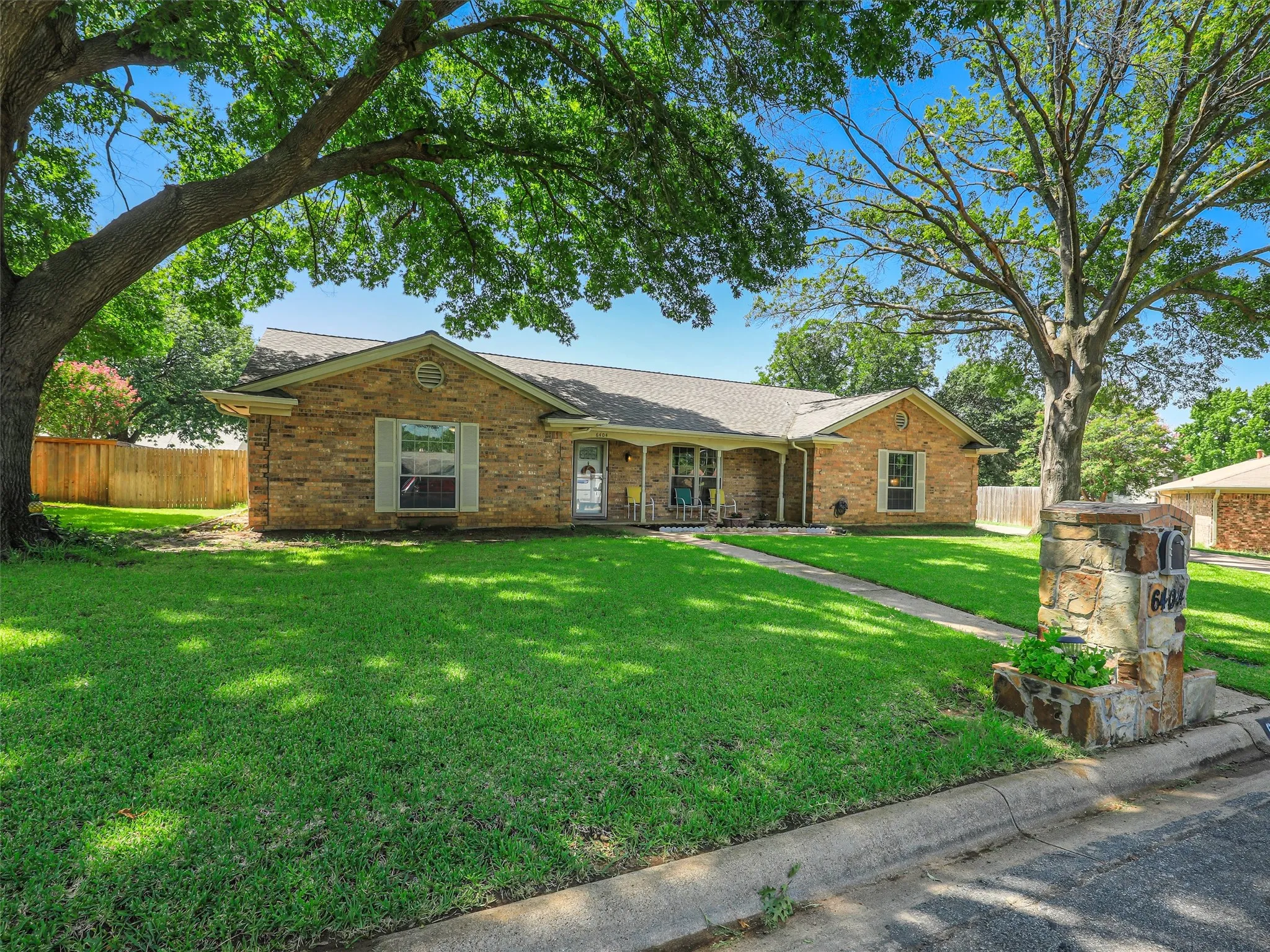Brick exterior residence featuring a covered front porch and green shutters