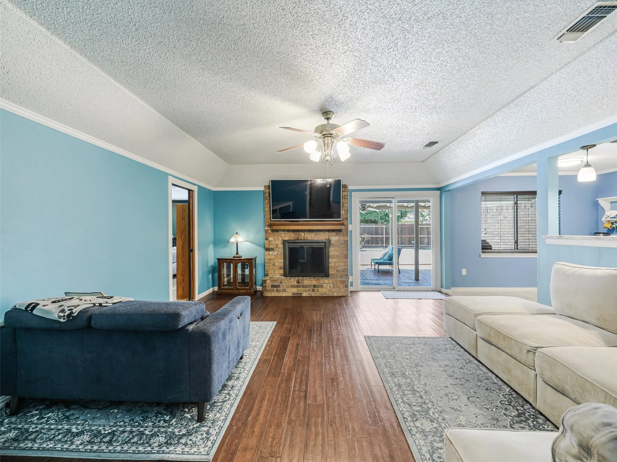 Living area featuring wood-finish flooring, a brick fireplace, and vaulted ceilings