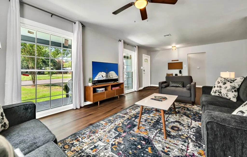 Bright living area featuring a ceiling fan with integrated lighting, and a large multi-pane window