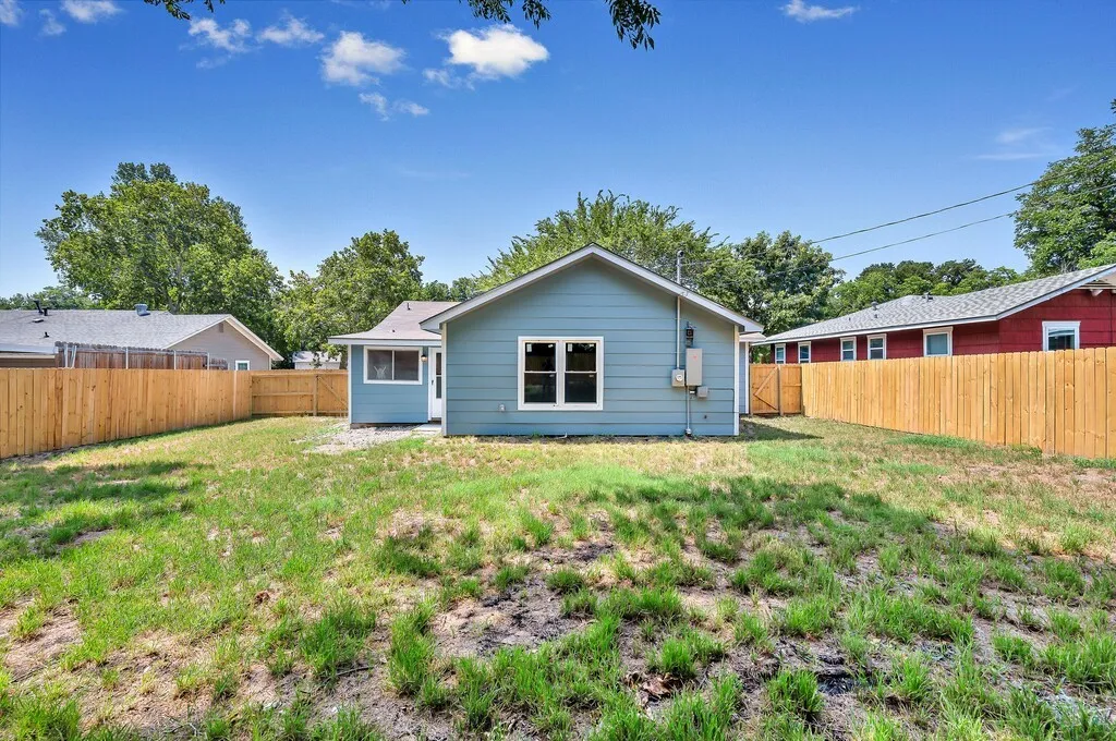 Spacious backyard featuring a new wood privacy fence, a light blue exterior, white trim, and multiple windows