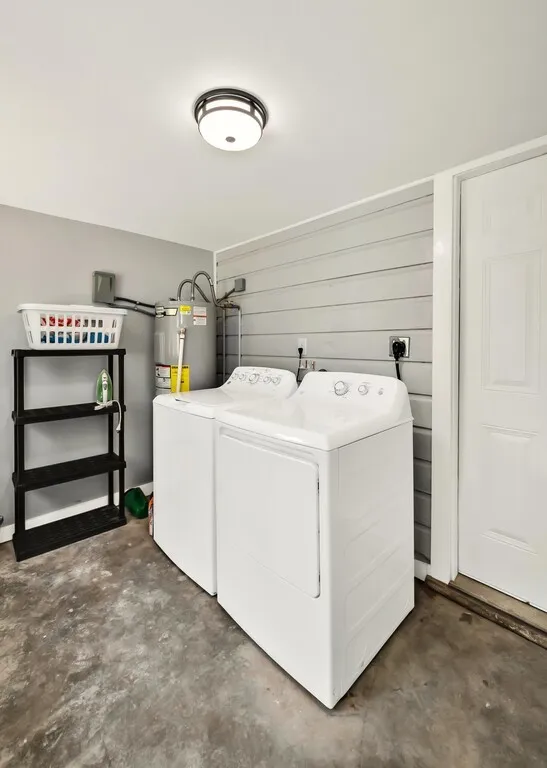 Dedicated utility area featuring a water heater, a modern flush-mount ceiling light fixture, and a durable concrete floor