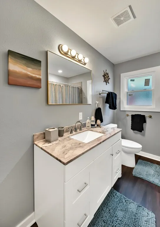 Bathroom featuring a white vanity with a stone countertop, an undermount sink
