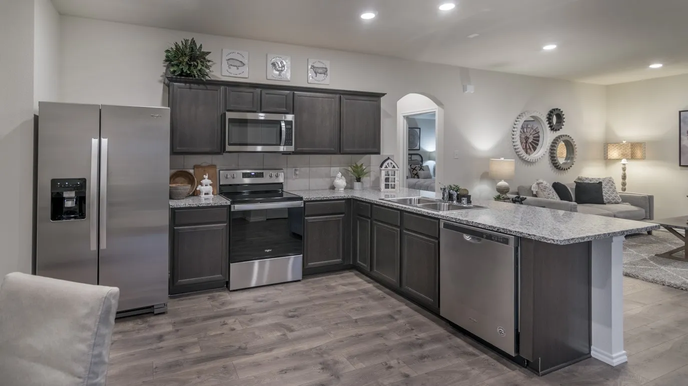 Well-appointed kitchen featuring wood-finish flooring, dark wood cabinetry, a light-toned countertop, and stainless steel appliances
