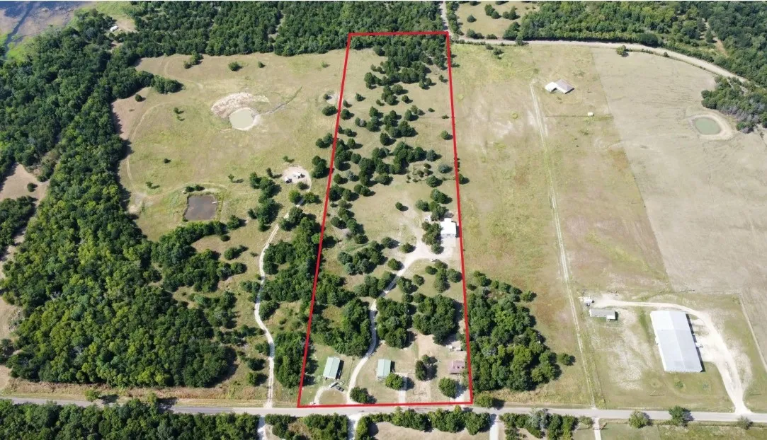 Aerial view of a sprawling property featuring a mixture of wooded and open land
