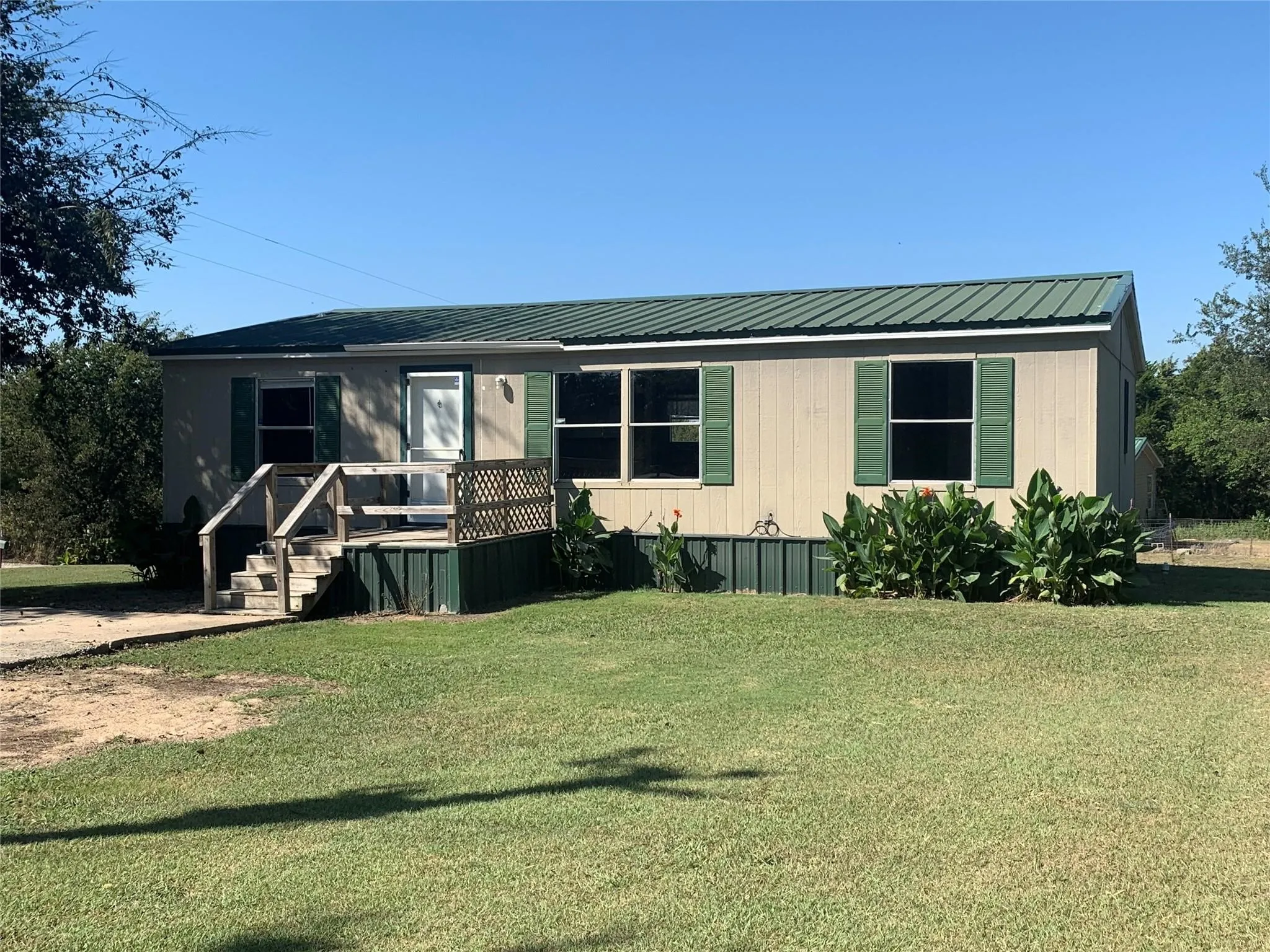 3 bedroom, 2 bath mobile home featuring a metal roof, beige siding, and green shutters