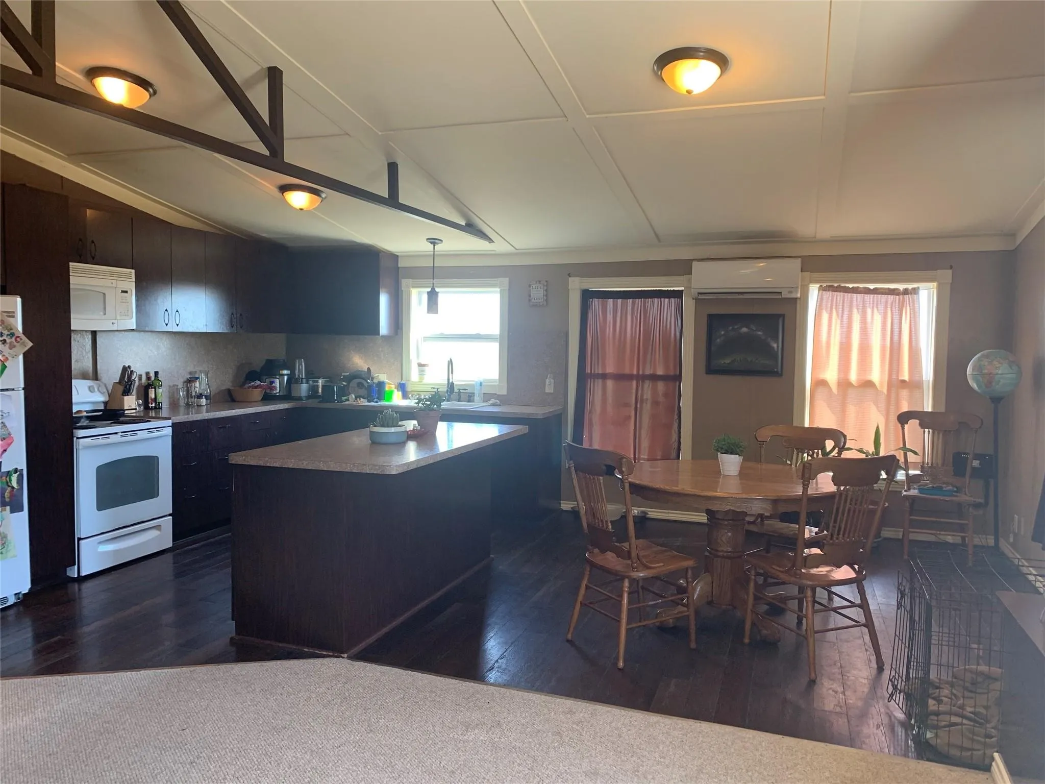 Open-concept kitchen and dining area featuring dark wood-finish cabinetry, a large kitchen island with a stone-finish countertop, wood-finish flooring, and recessed ceiling lighting