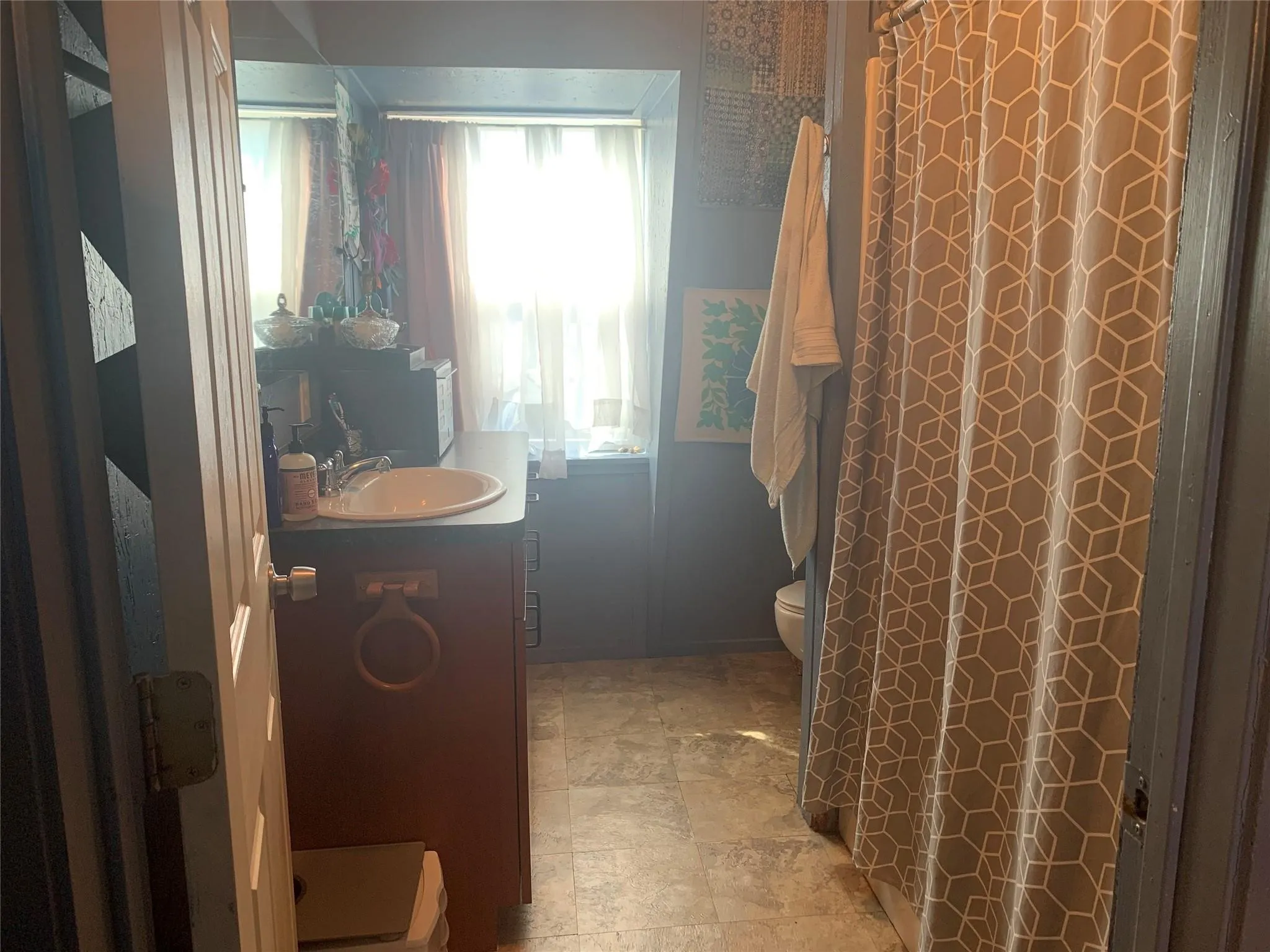 Cottage Bathroom featuring a built-in vanity with a white basin sink, dark countertop, and base cabinetry