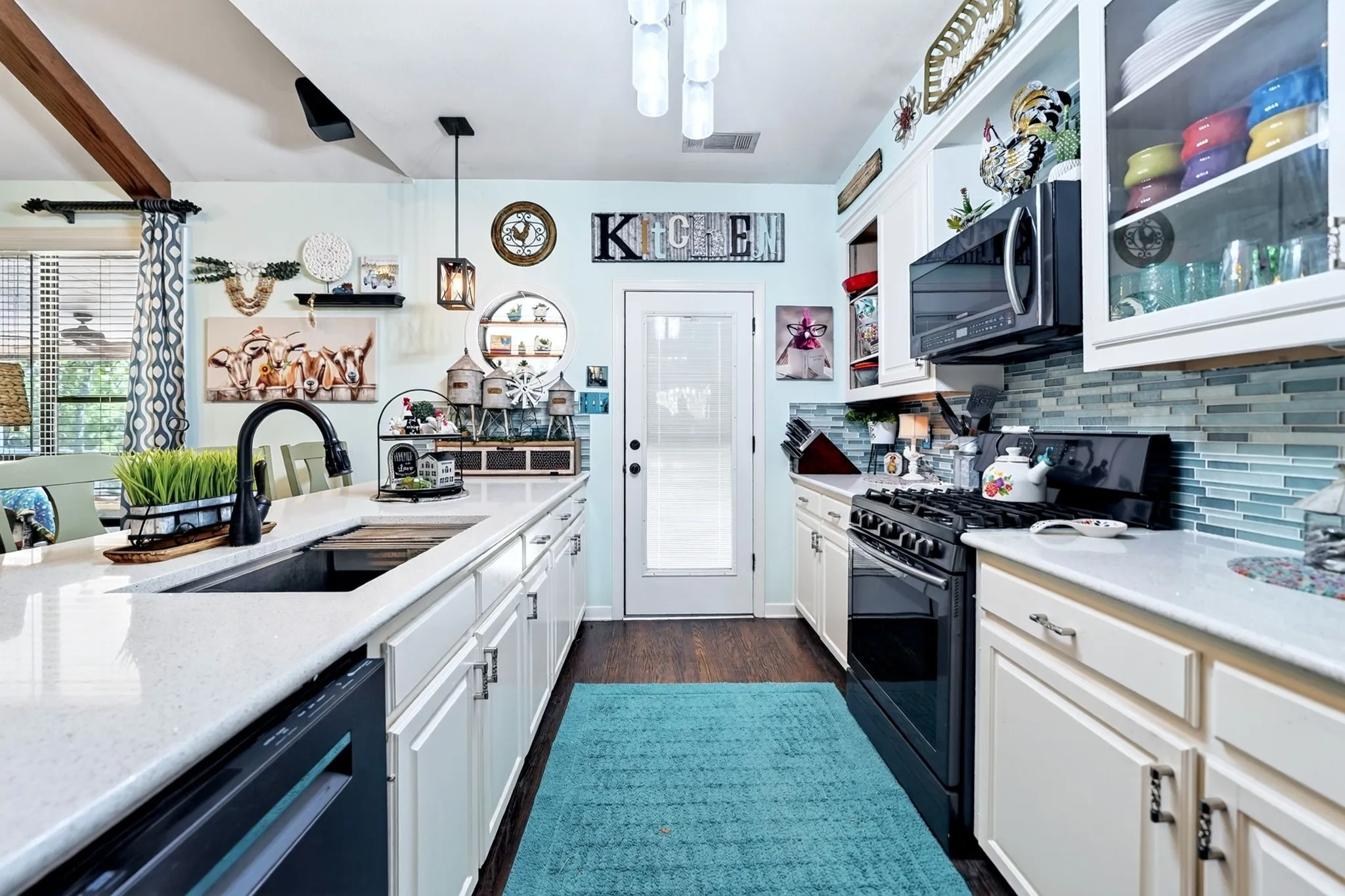 Kitchen featuring white cabinetry, light-toned countertops, a black gas range, a black built-in microwave, and a glass tile backsplash