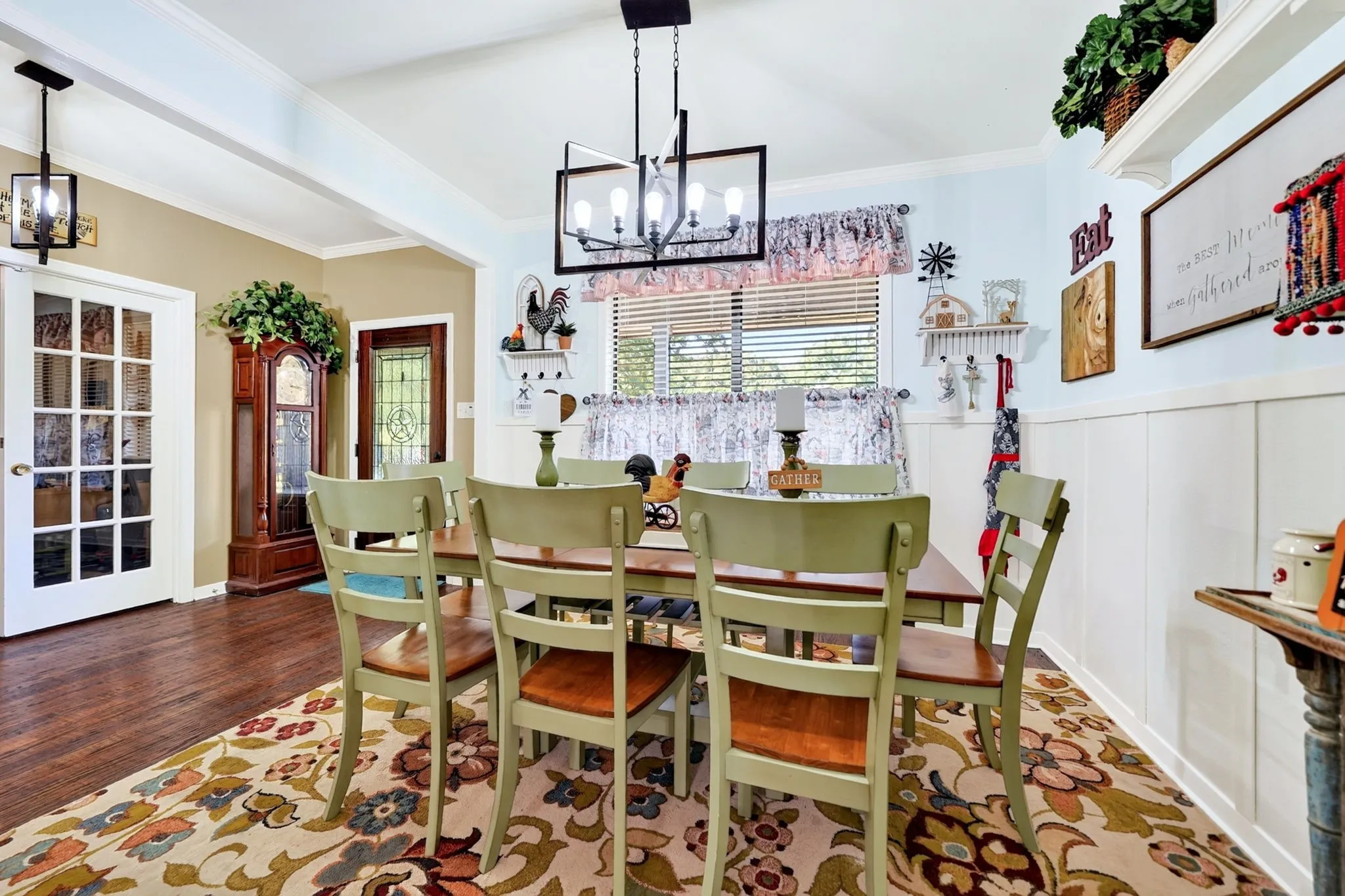 Dining area featuring a contemporary chandelier, board and batten wall treatment, and a window with blinds