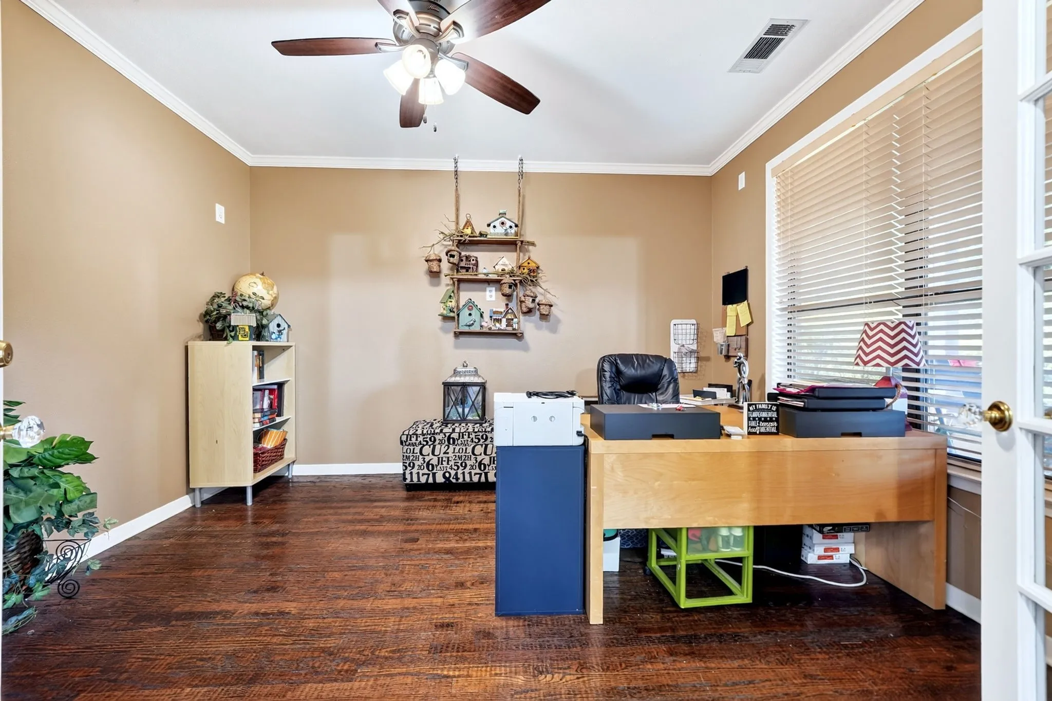 Spacious room featuring wood-finish flooring, neutral-toned walls, and white crown molding
