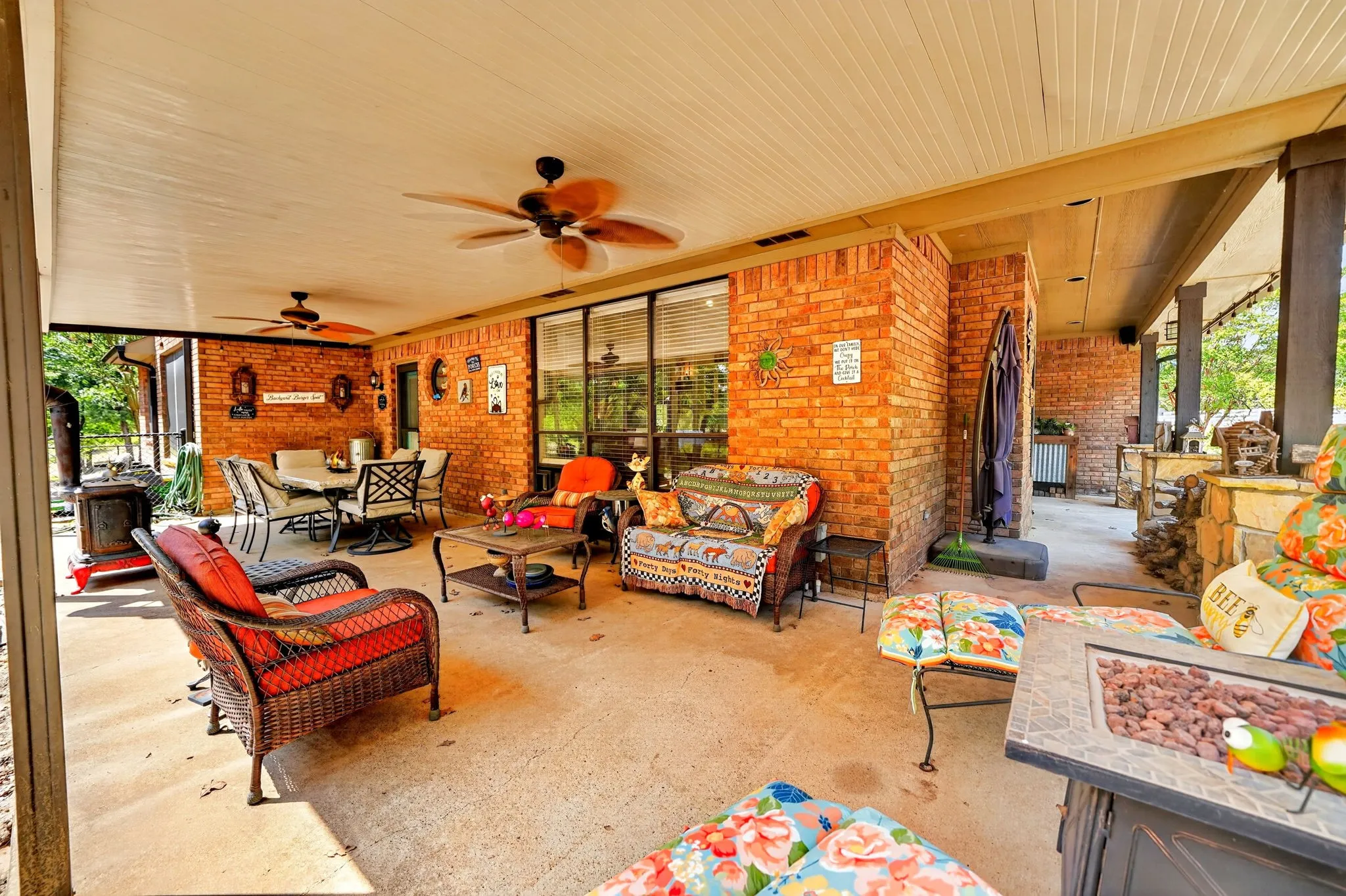 Expansive covered patio featuring a concrete floor, brick exterior walls, and a beadboard ceiling with two ceiling fans