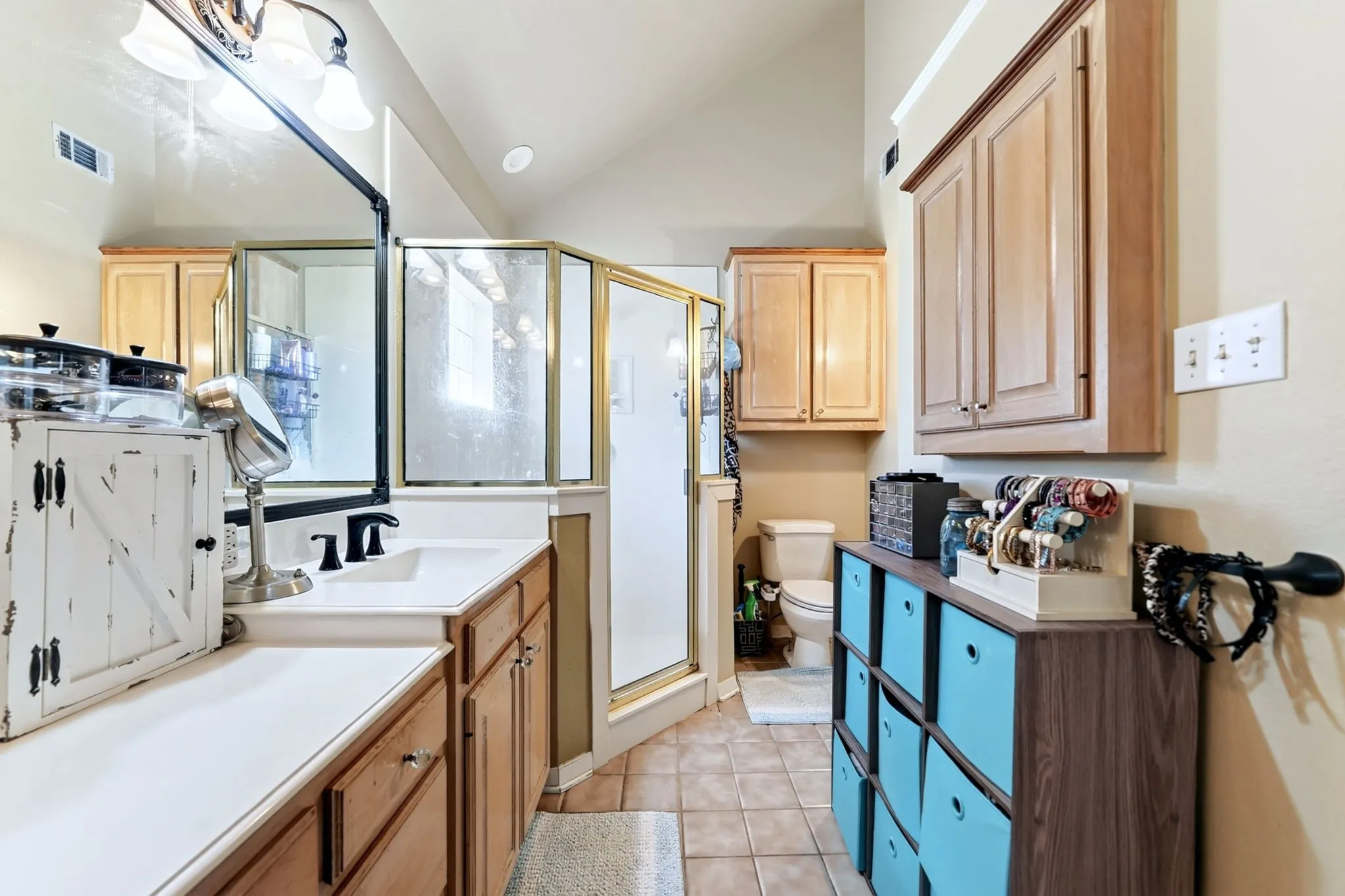 Bathroom featuring a shower enclosure, vanity with built-in storage, and tile flooring