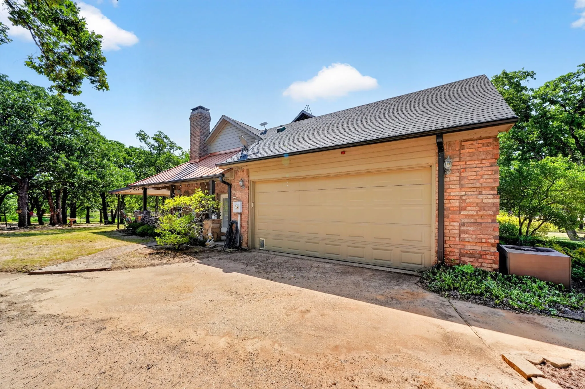 Exterior showcasing a two-car garage with a tan door, brick and siding facade, and an asphalt shingle roof