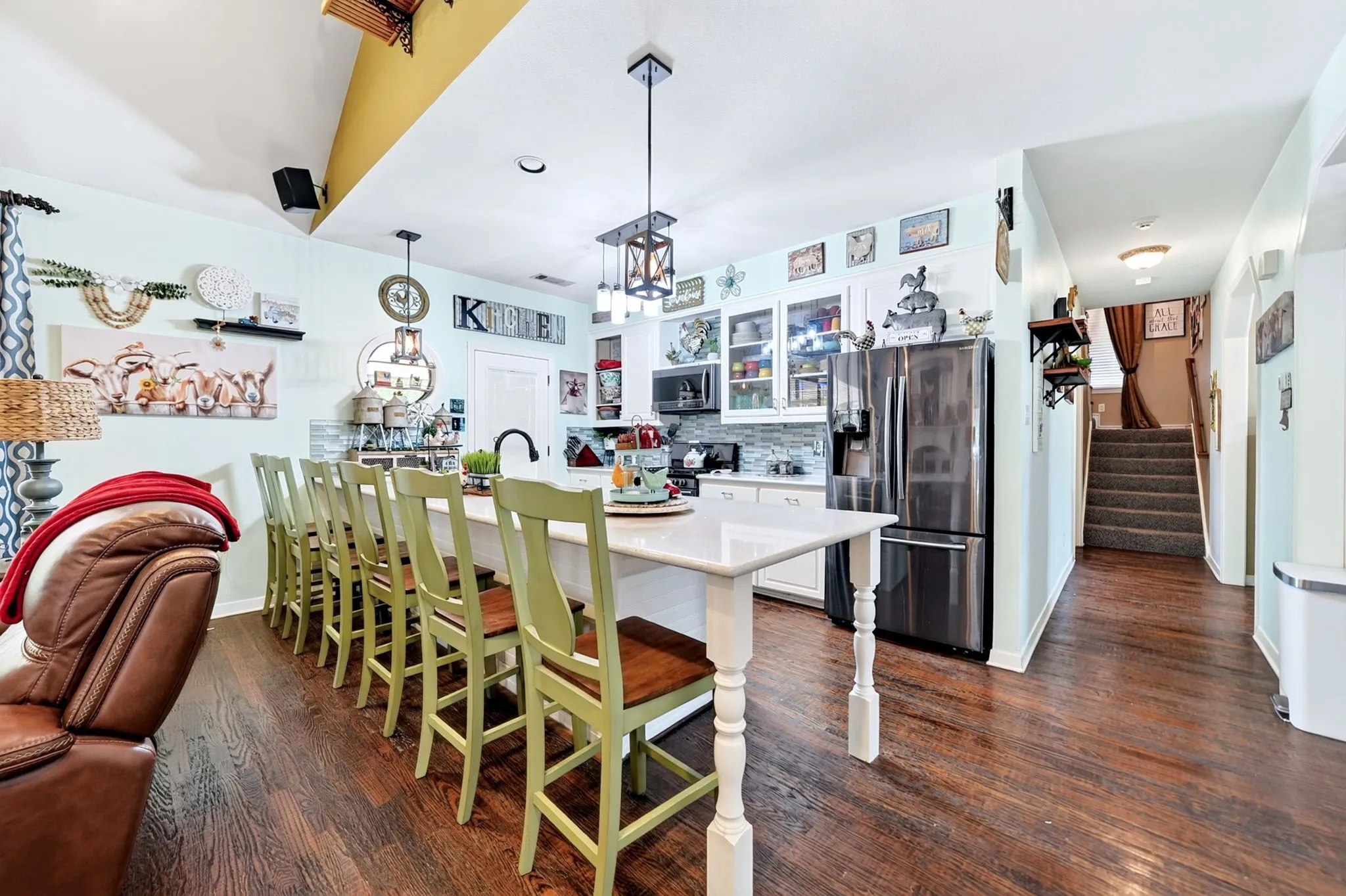 Open-concept kitchen featuring a large island with seating, stainless steel appliances, white cabinetry, and wood-finish flooring