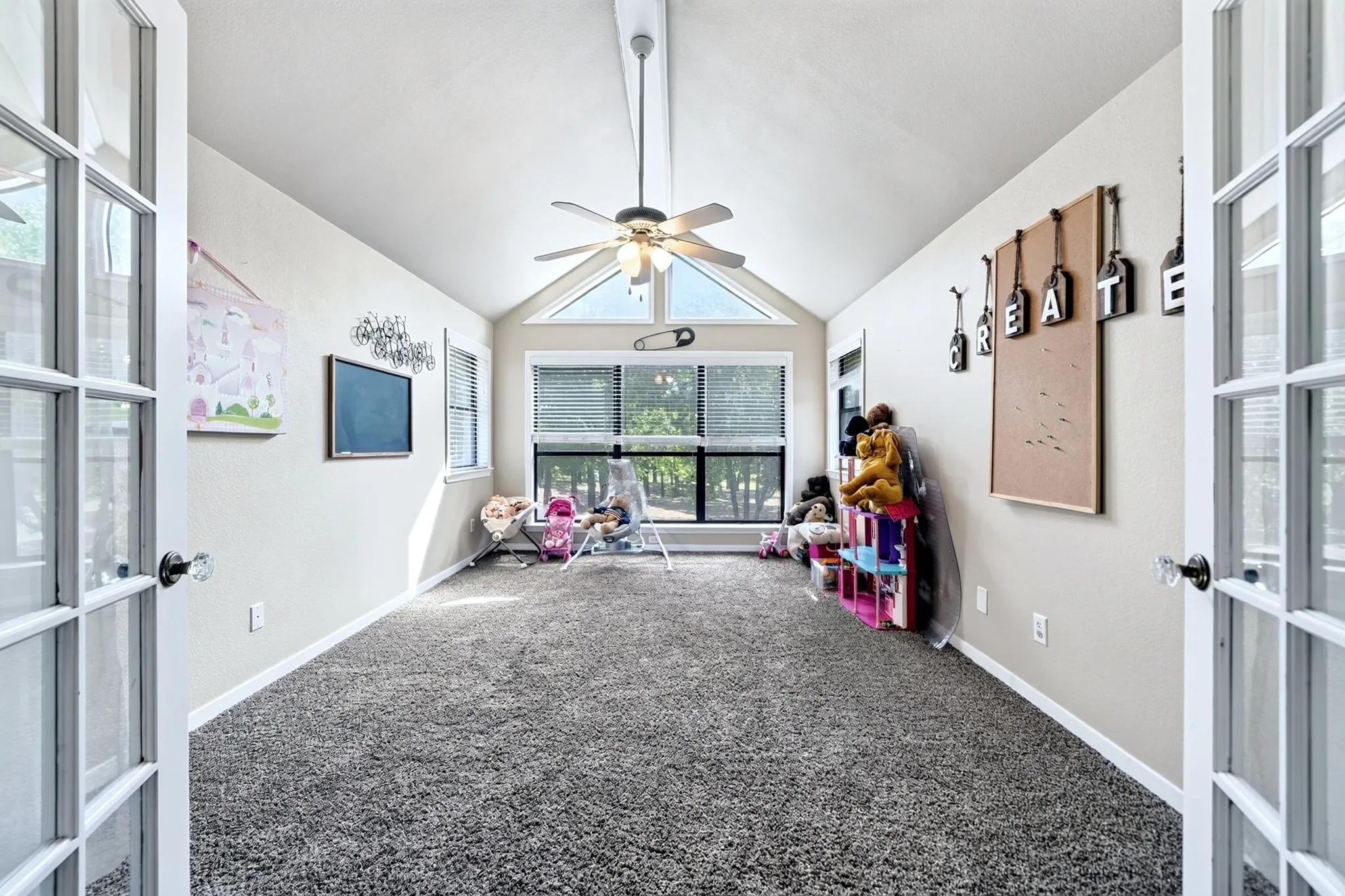 Room featuring vaulted ceilings, a large picture window, and a ceiling fan