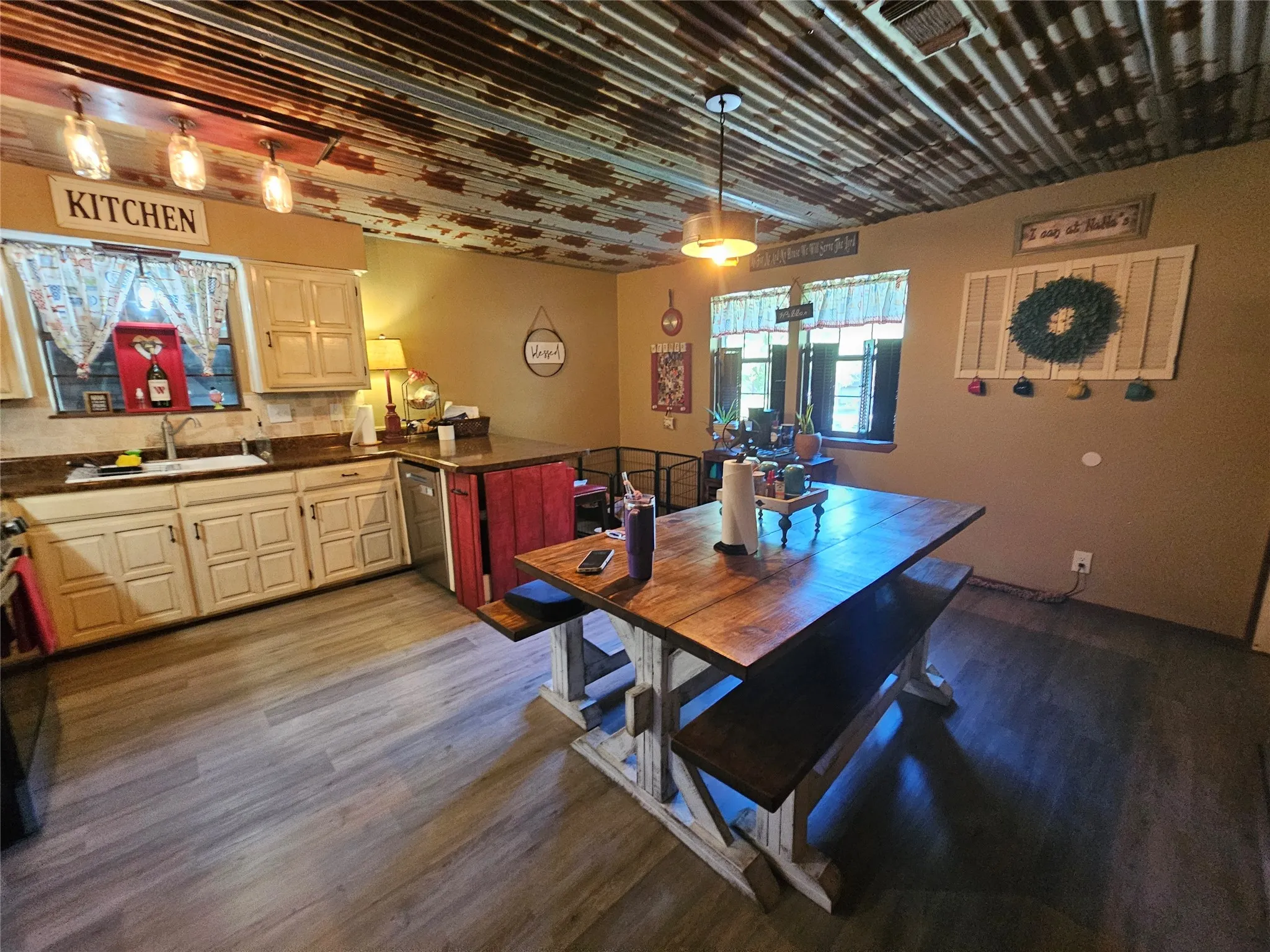 Kitchen featuring a corrugated metal ceiling with patina finish, wood-finish flooring, cream-toned cabinetry, and a built-in kitchen island with a red paneled base