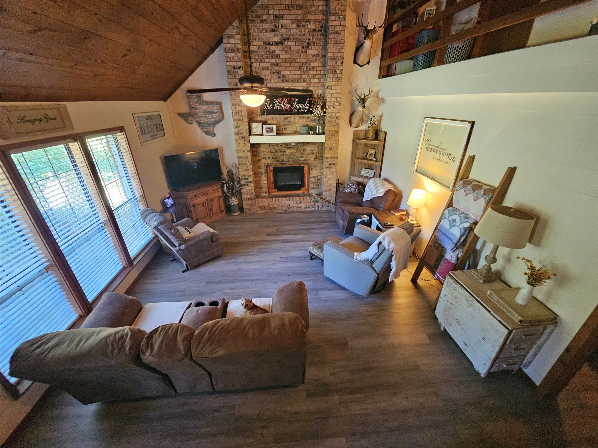 Vaulted ceilings featuring wood-finish paneling and a brick fireplace