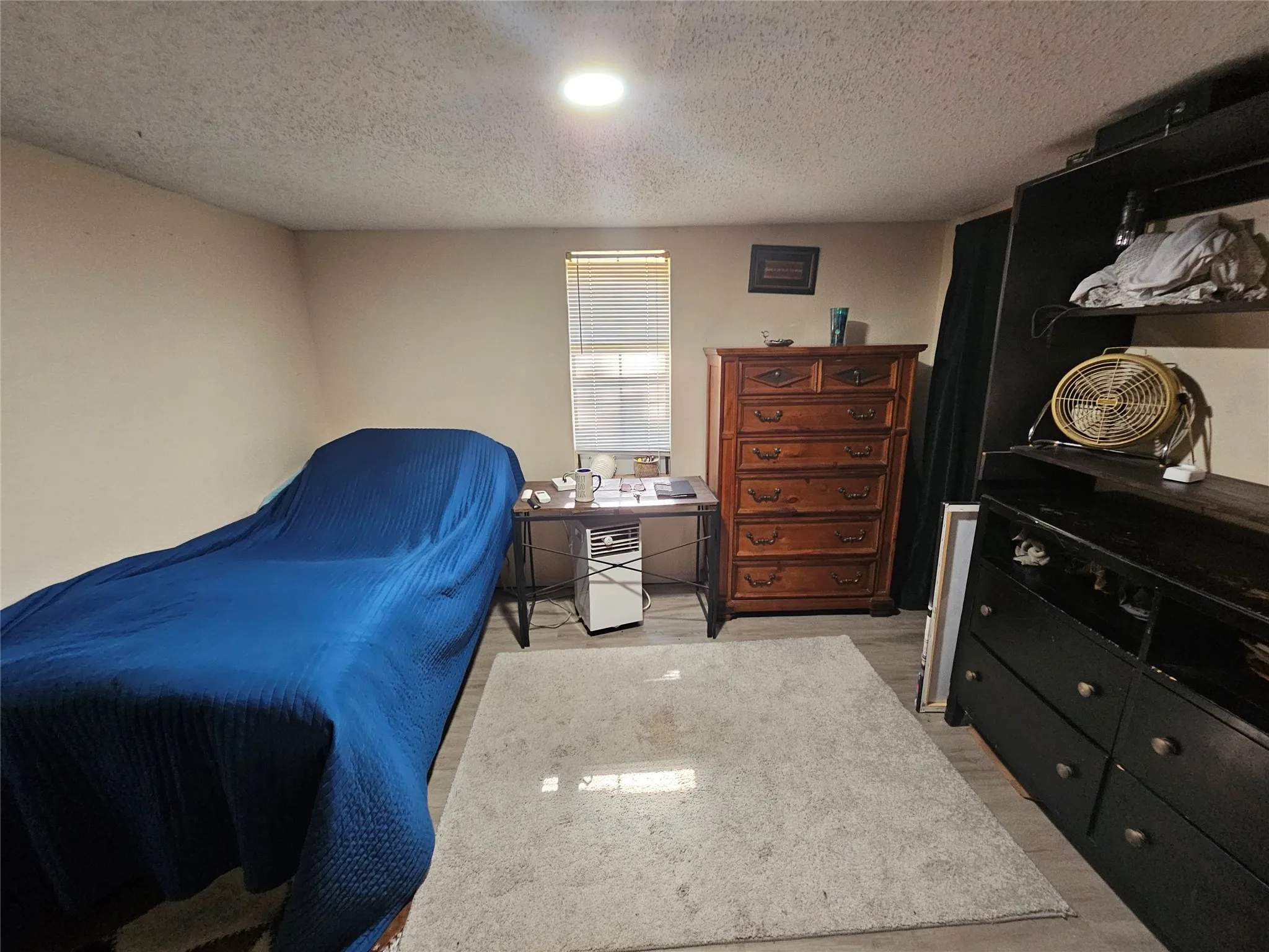 Recessed lighting illuminates this room featuring light-colored walls and wood-finish flooring