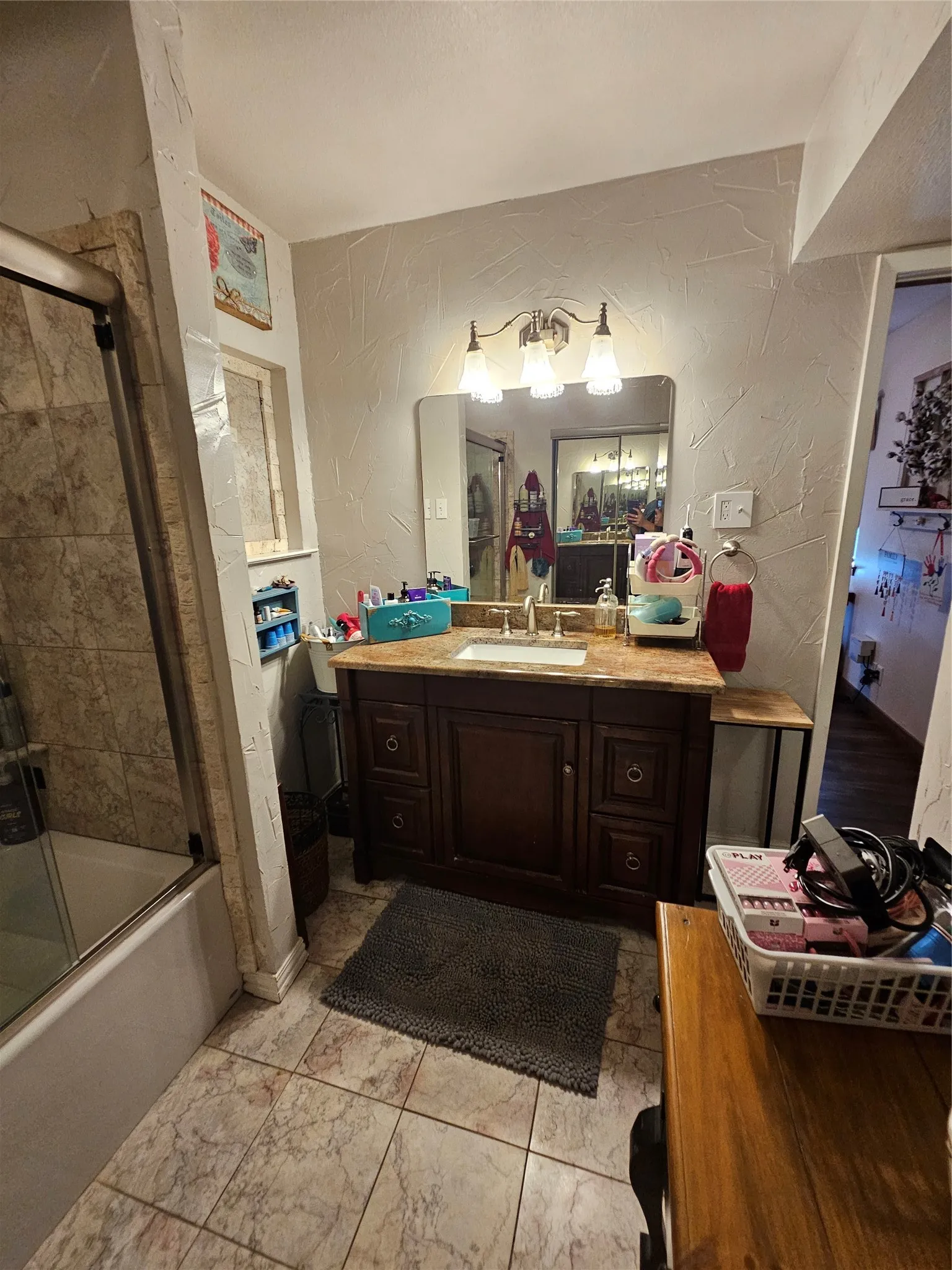 Bathroom featuring a dark wood-finish vanity with a light stone-finish countertop, undermount sink, and wall-mounted vanity lighting