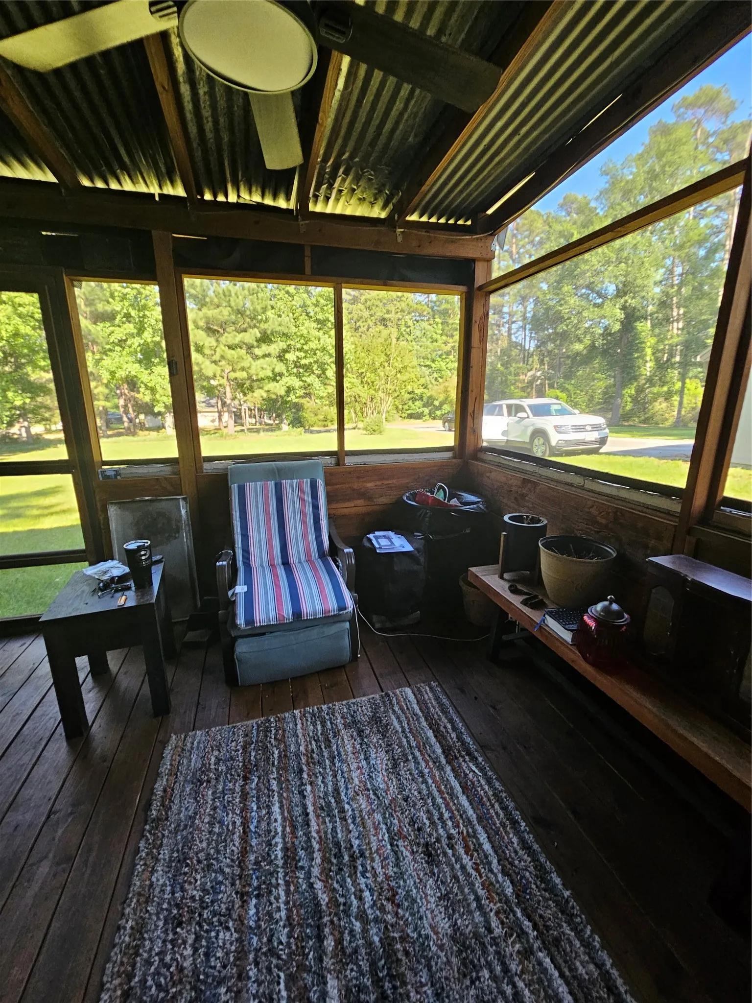 Screened porch featuring wood-finish flooring, a corrugated metal ceiling, exposed wood beams, and a ceiling fan