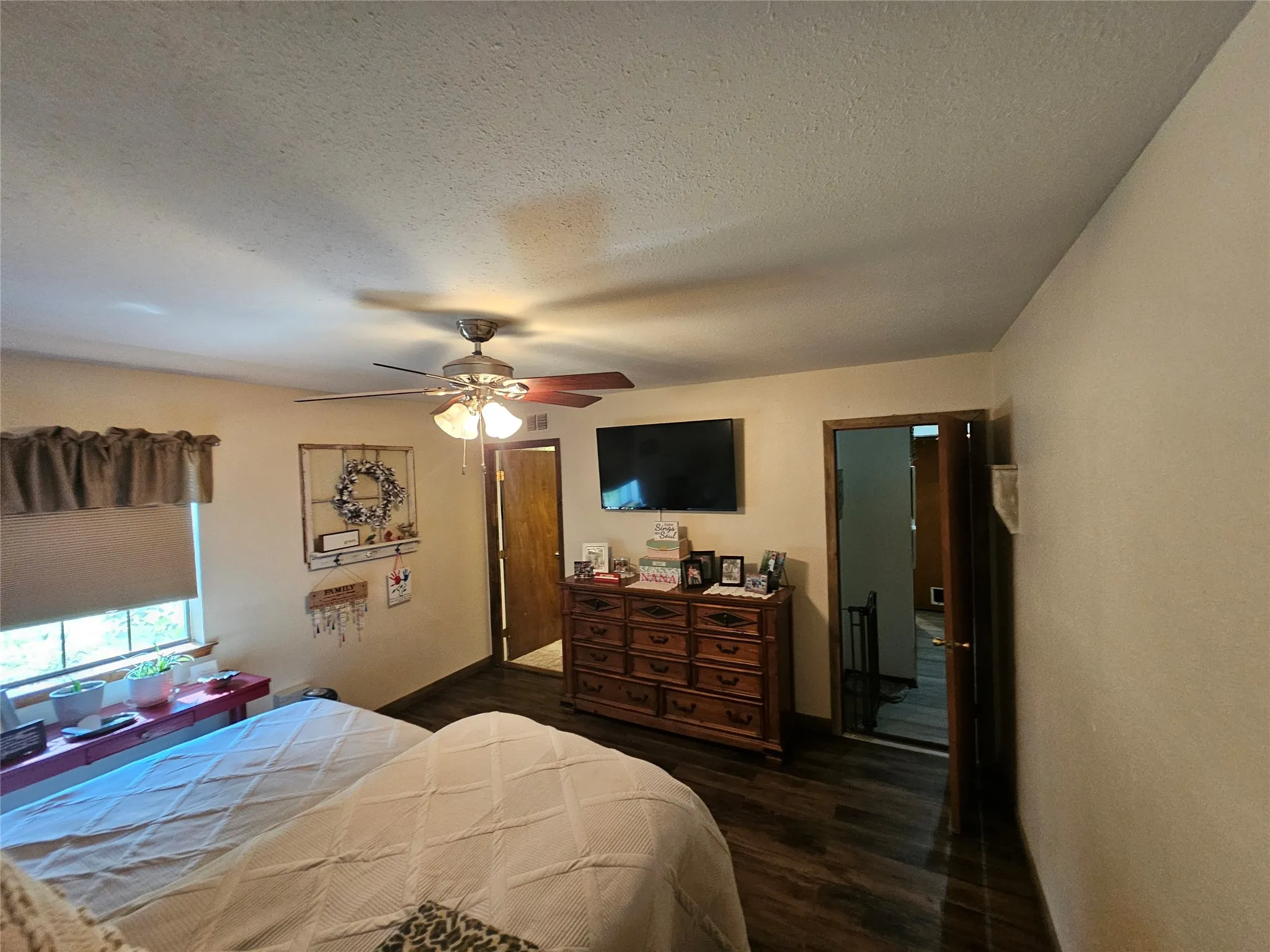 Room featuring dark wood-finish flooring, a ceiling fan with integrated lighting, and neutral-toned walls