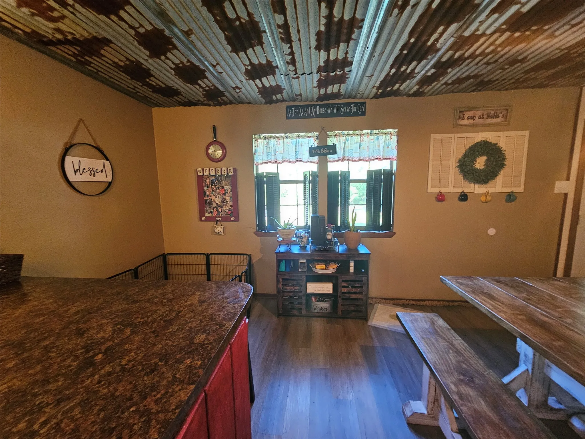 Corrugated metal ceiling treatment, wood-finish flooring, and a window with dark shutters