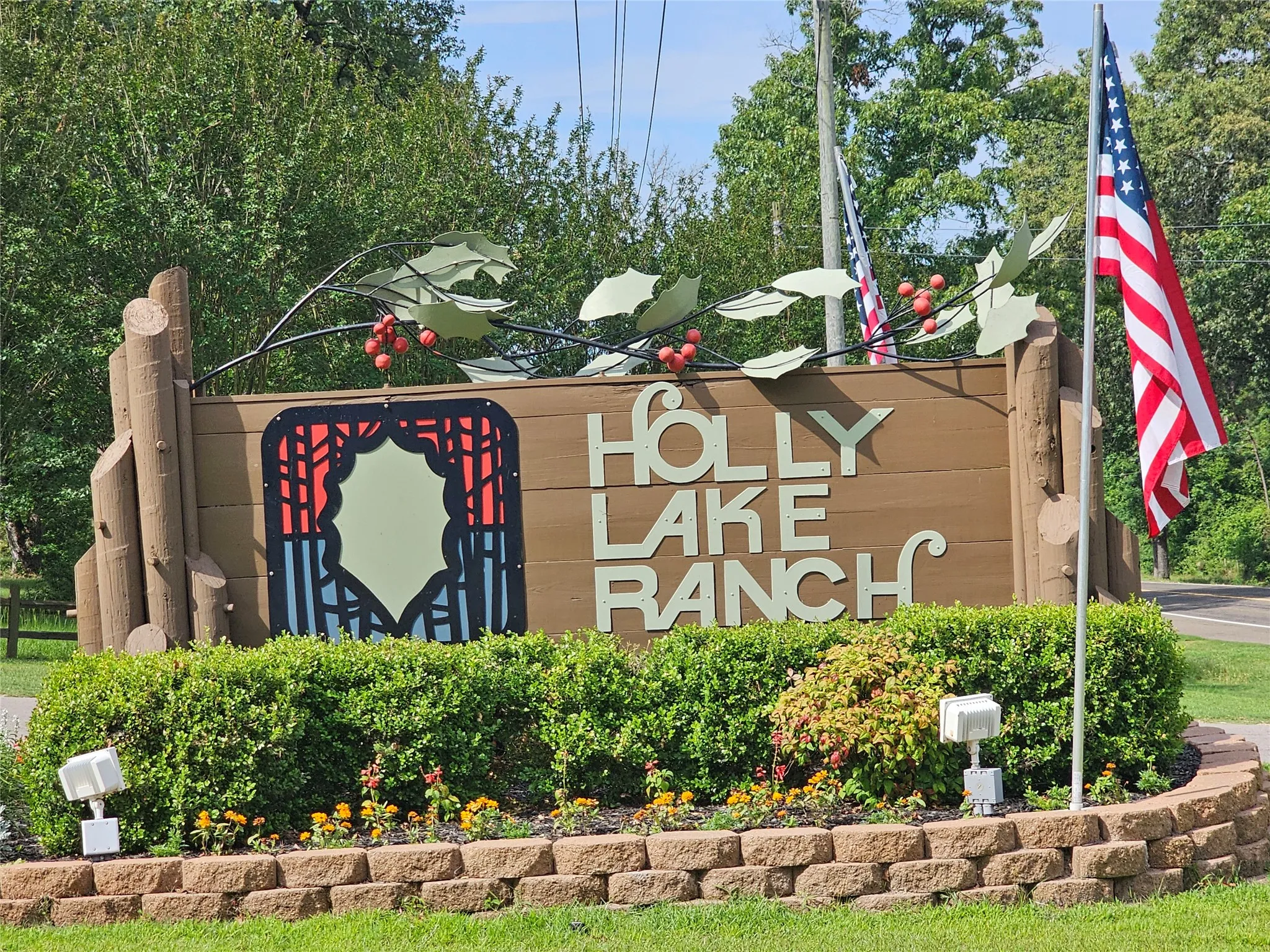 Holly Lake Ranch entrance sign featuring a decorative metal holly branch accent